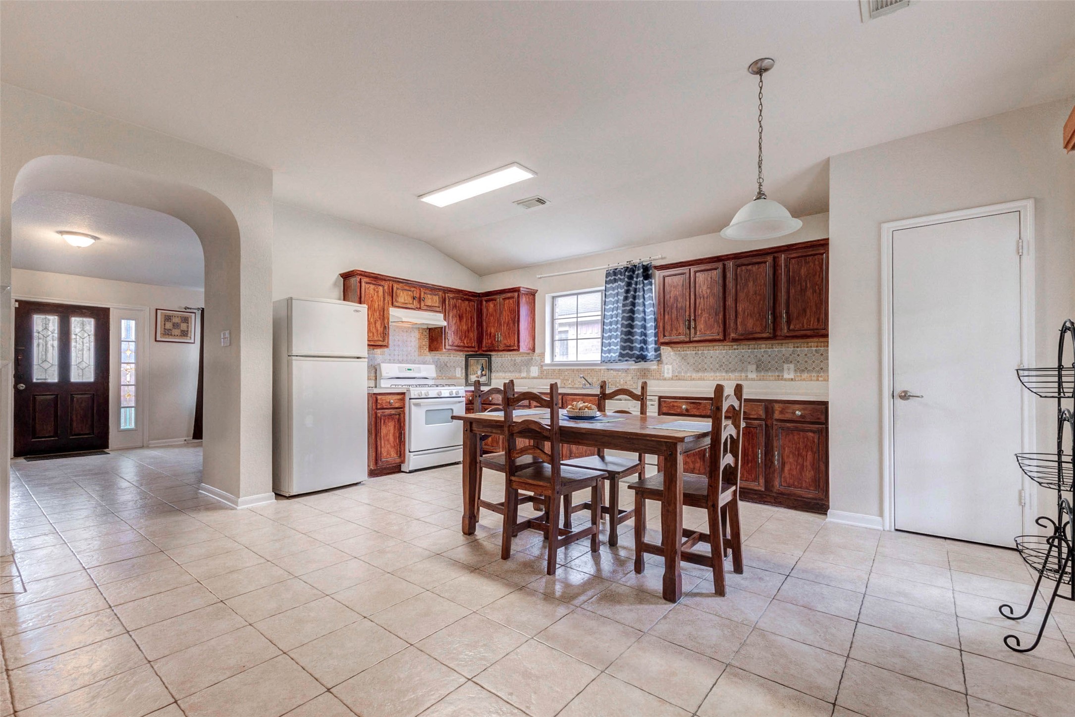 Open-concept kitchen and dining space with generous cabinet storage and a functional layout. The combination of natural light, tile flooring, and warm wood tones creates an inviting atmosphere. Easy access to nearby living areas enhances flow, making this a central hub for daily living and entertaining alike.
