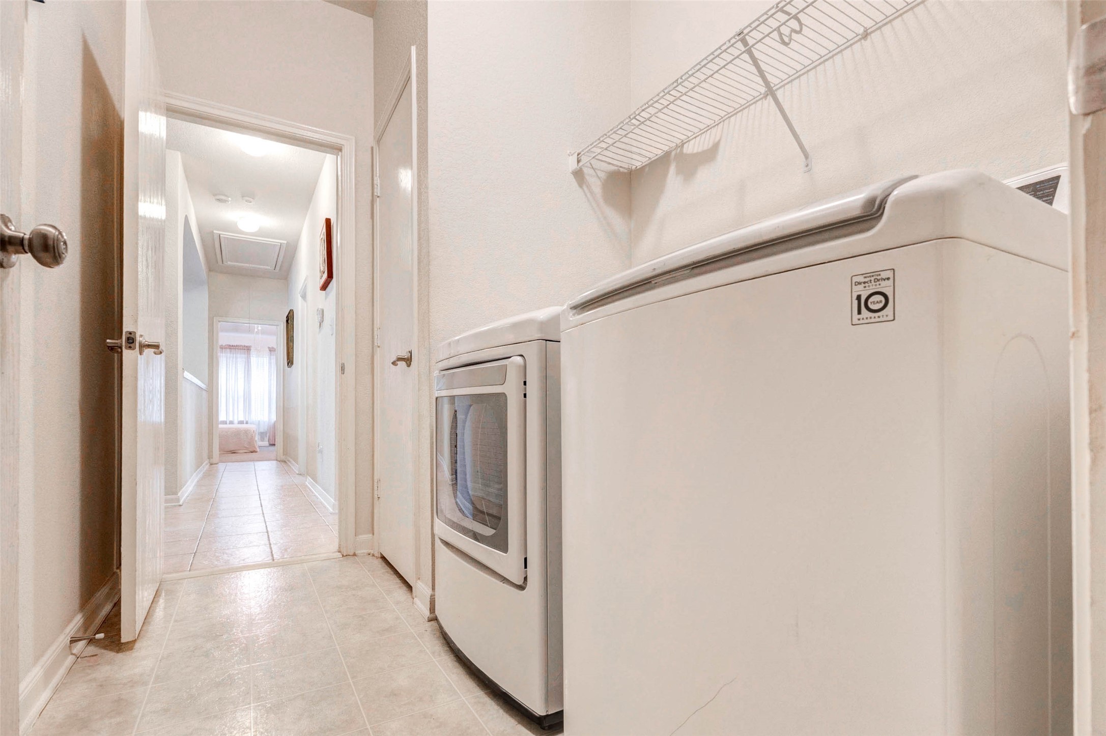 Functional utility area with convenient in-home laundry setup, offering both washer and dryer. Overhead shelving provides additional storage for supplies, while the layout ensures easy access without disrupting main living areas. A practical and efficient space designed to support everyday household needs.