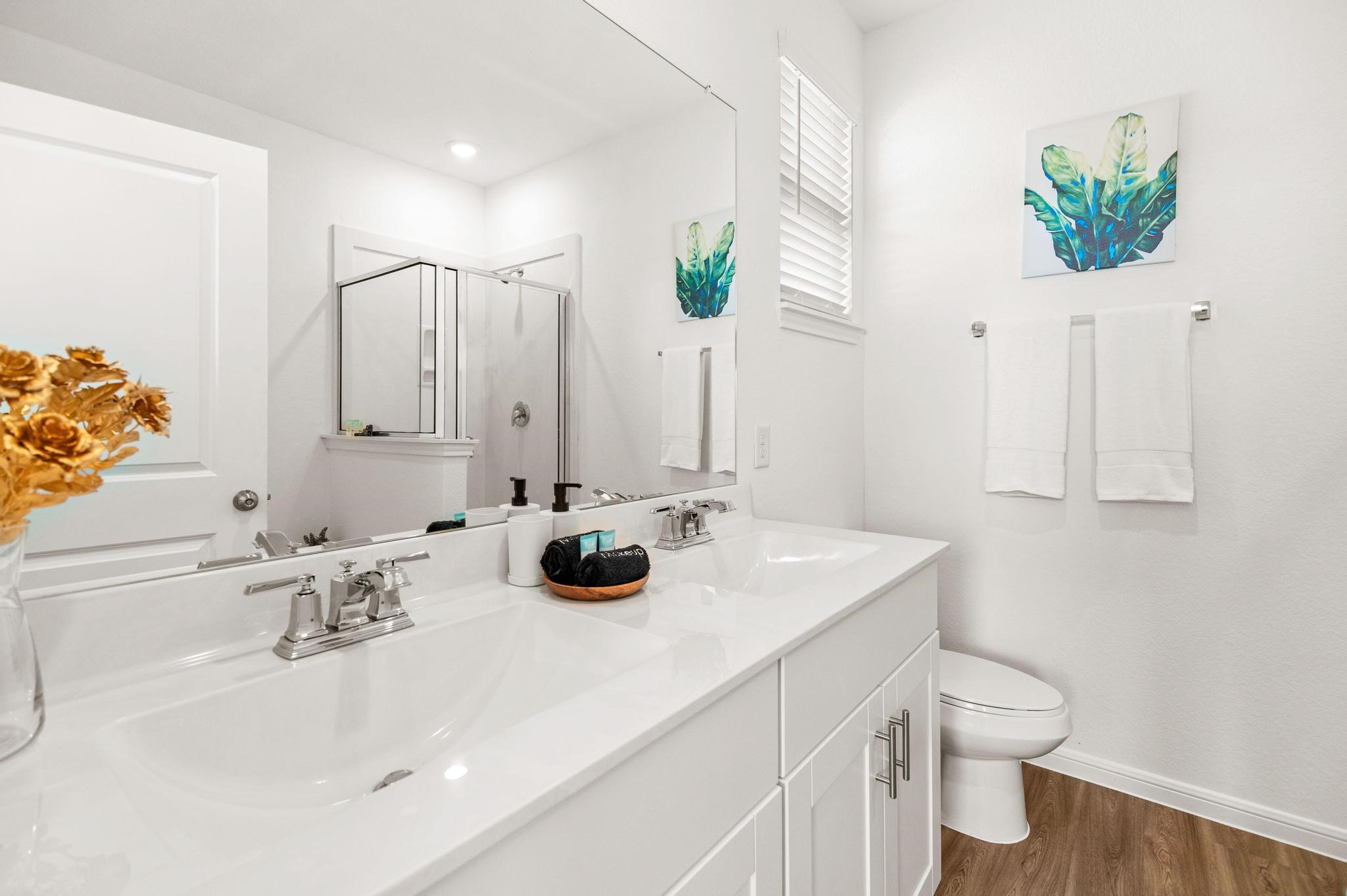 Bright and modern bathroom featuring a double vanity with sleek fixtures, a spacious shower, and elegant decor.