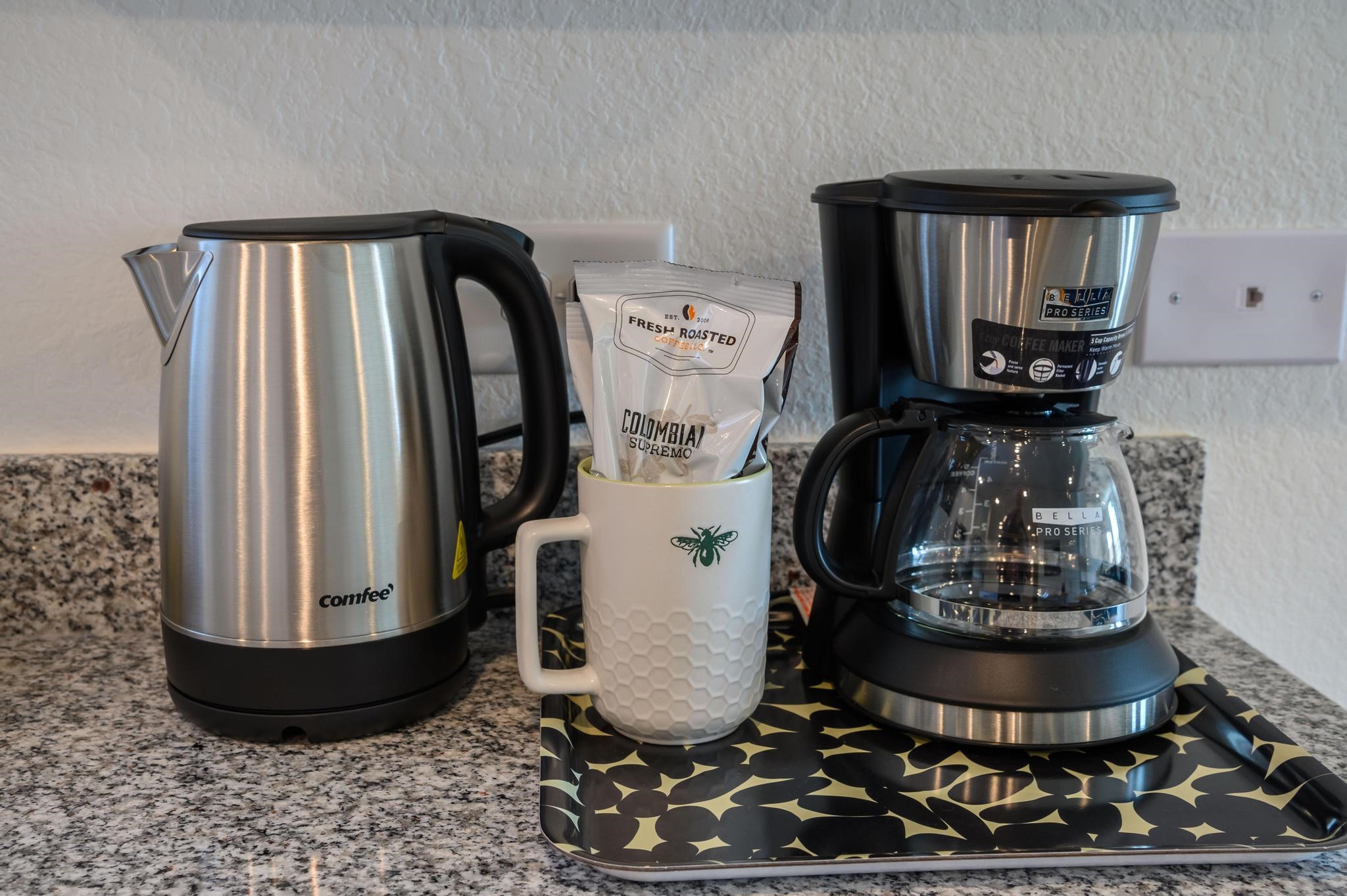 Modern kitchen setup featuring a sleek stainless steel kettle and coffee maker on a stylish granite countertop, perfect for your morning routine.