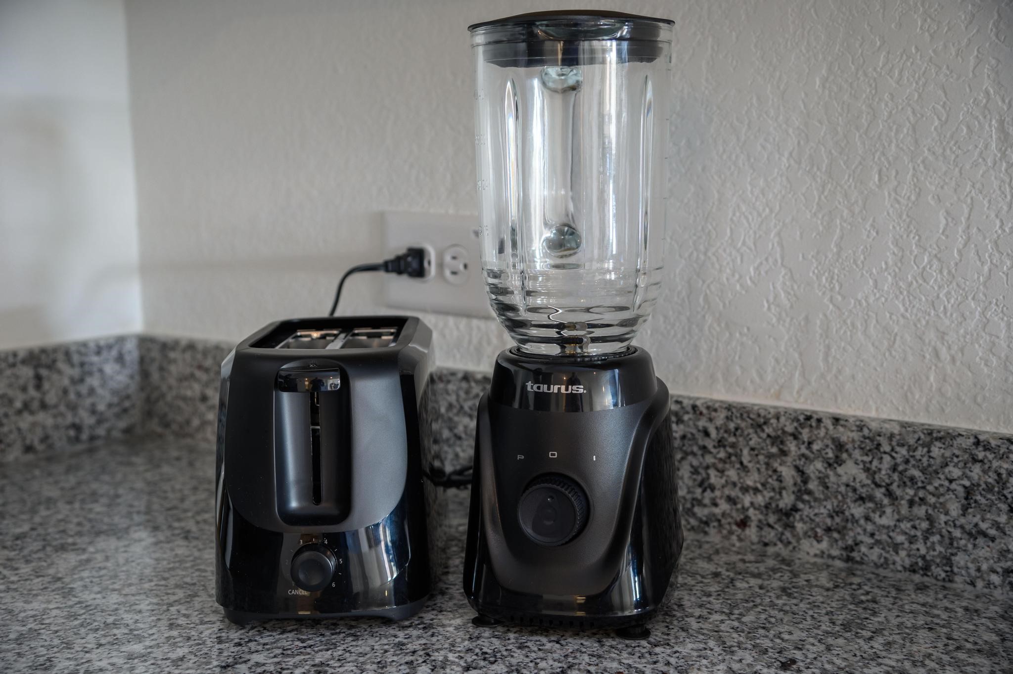 Modern kitchen corner with sleek granite countertops, featuring a black toaster and blender for convenient meal preparation.