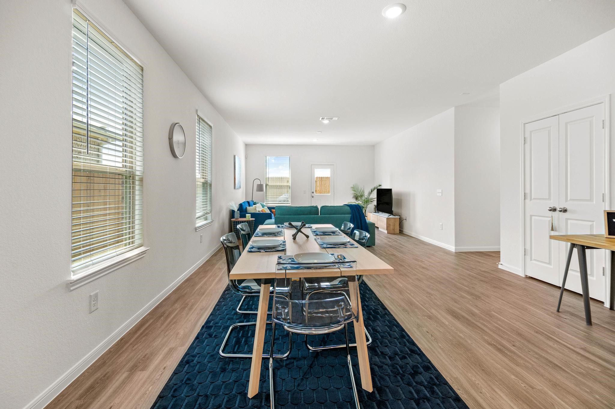 Bright open-concept living and dining area featuring modern furnishings, large windows, and sleek wood flooring perfect for entertaining.
