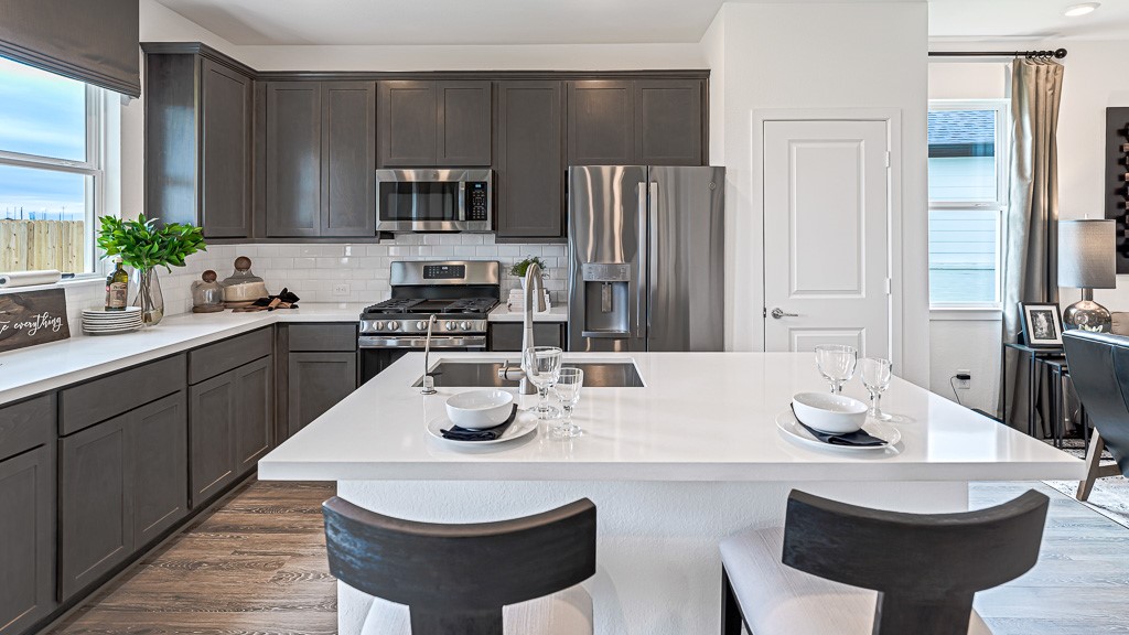 Well laid out kitchen designed for efficiency, convenience, and beauty, has ample counter/cabinet space and a walk-in pantry. Modern dark gray cabinets look sharp with white quartz counters and subway tile backsplash.