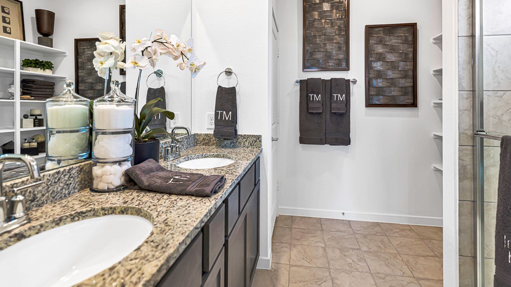 Primary ensuite has double vanities with modern silver fixtures and black cabinetry.