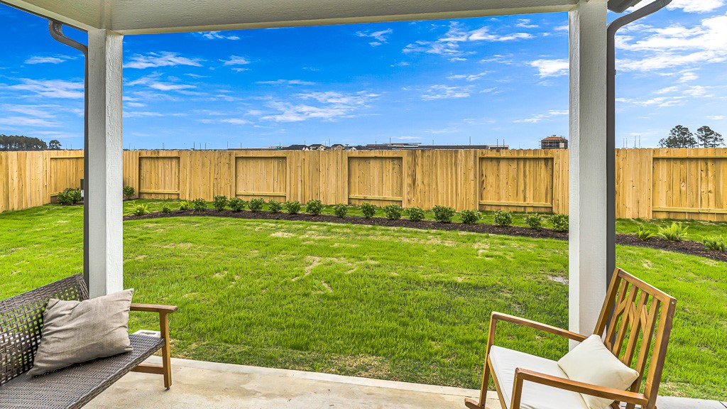 Welcoming backyard has a good neighbor fence with landscaped beds adding color, softness and texture to green lawn.