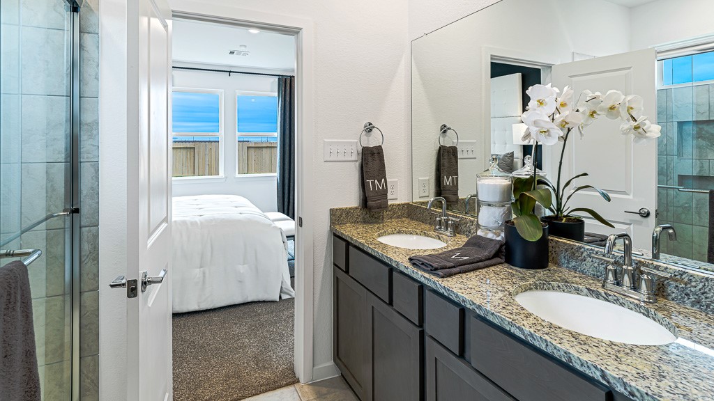 Walk-in shower has recessed shelves for bottles and a glass enclosure.