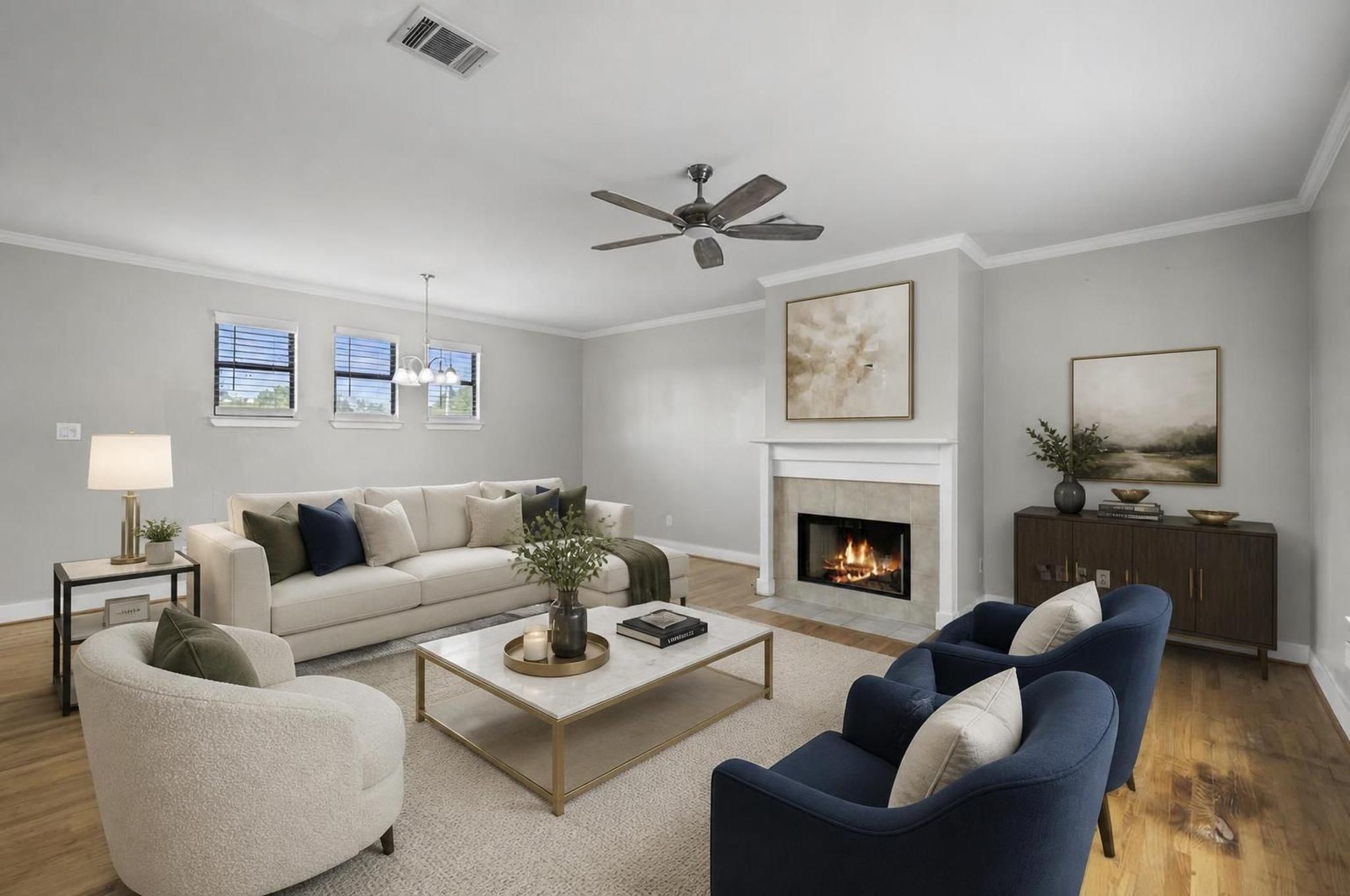 The living room opens on the second floor with wood flooring, high ceilings, crown molding, and a gaslog fireplace that anchors the space. It feels bright, refined, and comfortable without losing its sense of warmth. Virtually staged.