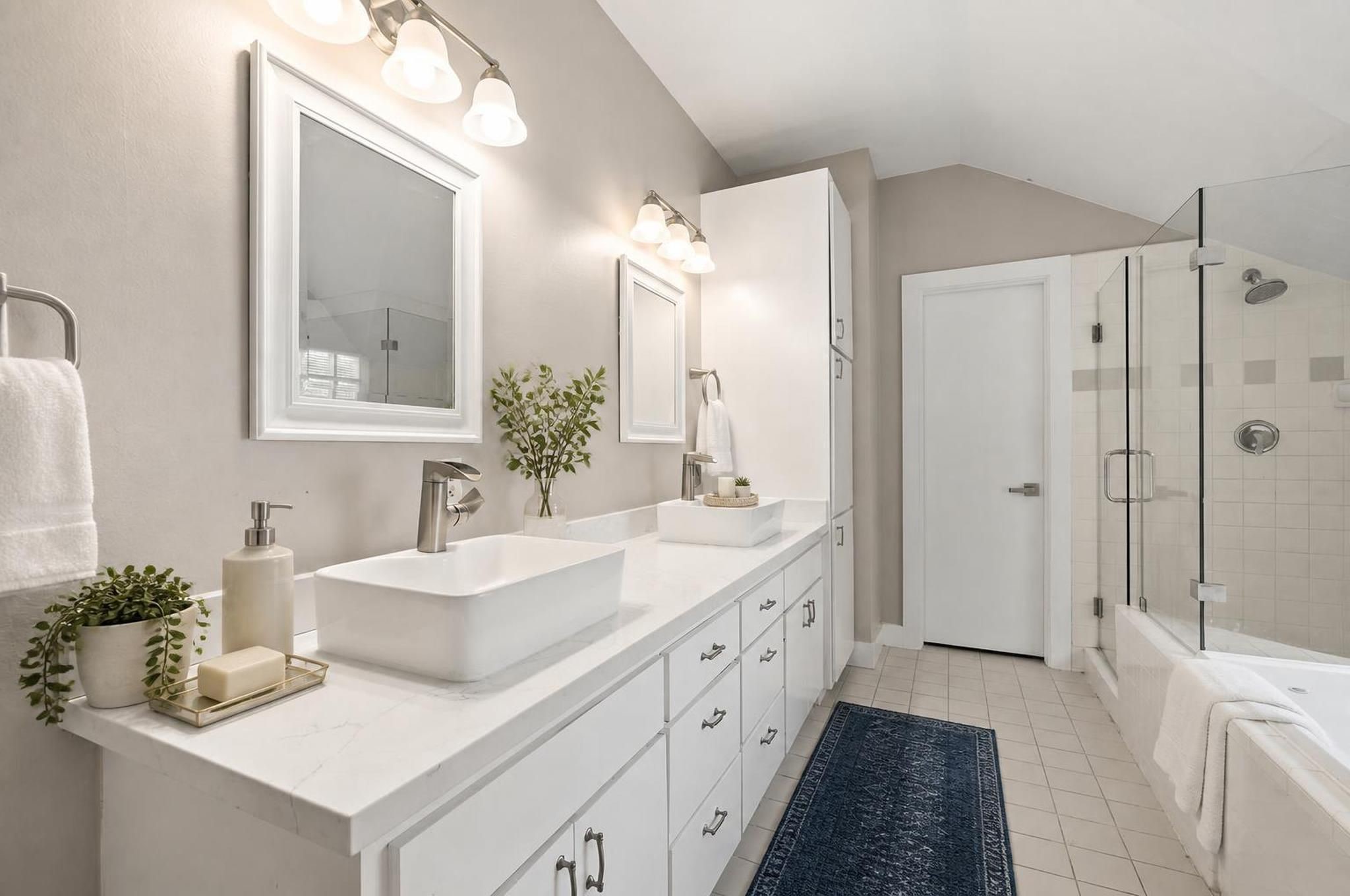 The primary bathroom feels spacious and complete with double sinks, a jetted tub, and a separate shower. It brings comfort and function together in a clean ensuite setting. Virtually staged.