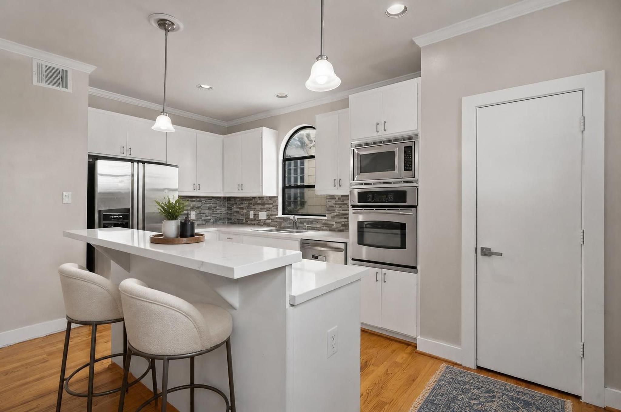 The kitchen brings a crisp, modern feel to the center of the home with quartz countertops, a breakfast bar, and an island with cooktop. Its open placement keeps the space connected to both dining and living. Virtually staged.