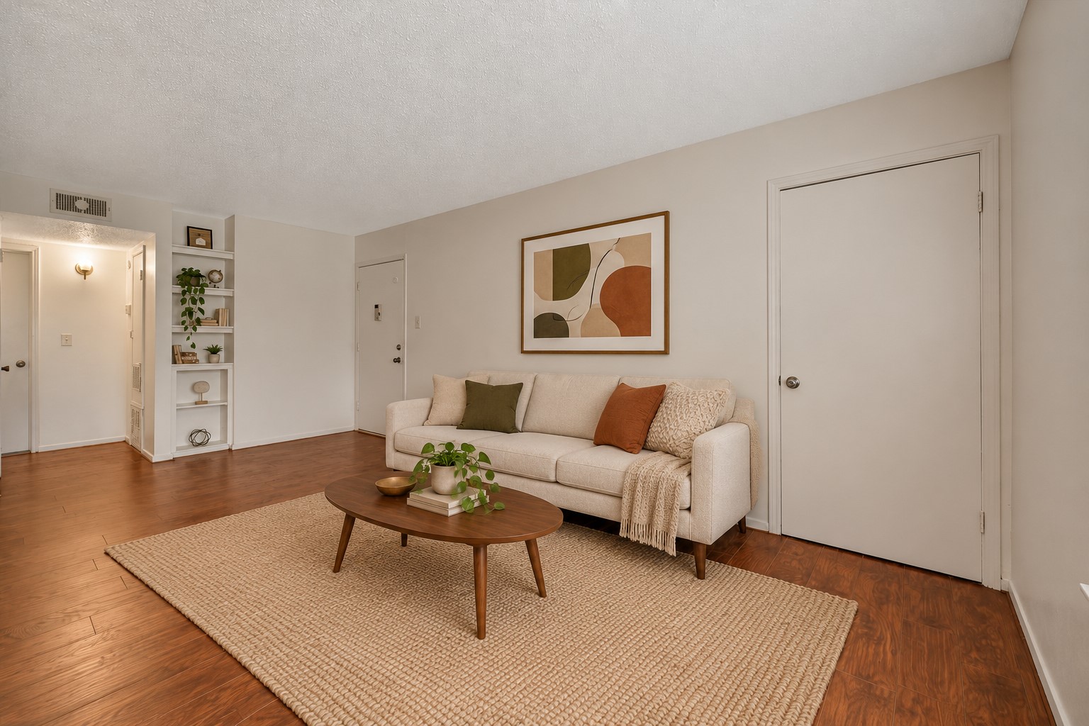 Opposite view of the living room highlights the entry door with convenient shelving to the leftperfect for organizing essentials. Virtually staged.