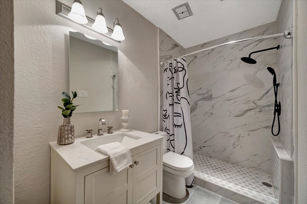 Step into this beautifully remodeled bathroom, featuring an enlarged tiled shower with modern finishes and a sleek, contemporary design.