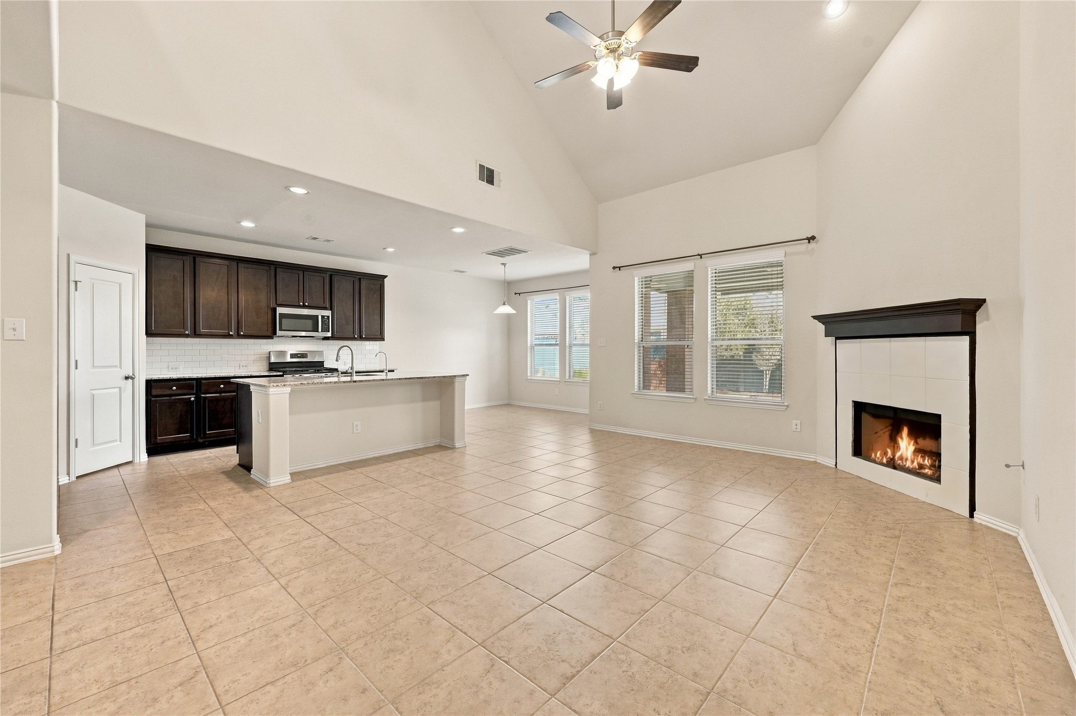 This stunning open concept living area features soaring ceilings, abundant natural light, and a cozy fireplace, flowing seamlessly into the kitchen and dining space. Perfect for everyday living and entertaining!
