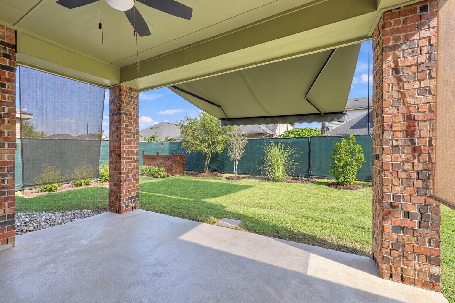 Covered patio featuring a retractable awning that can be extended for extra shade on sunny days. Perfect for relaxing or entertaining while overlooking the beautifully maintained backyard!