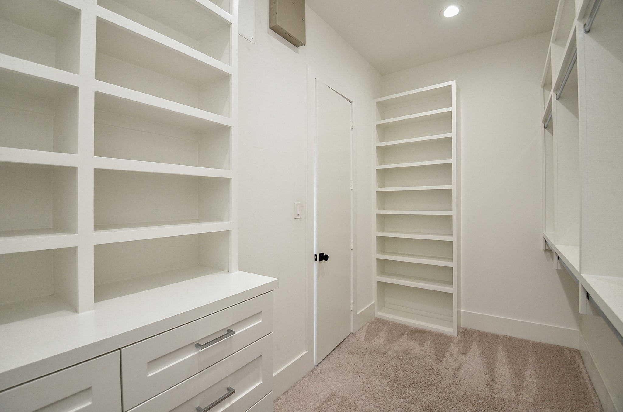 Primary walk-in closet with built-in drawers, shelving, and hanging storage.