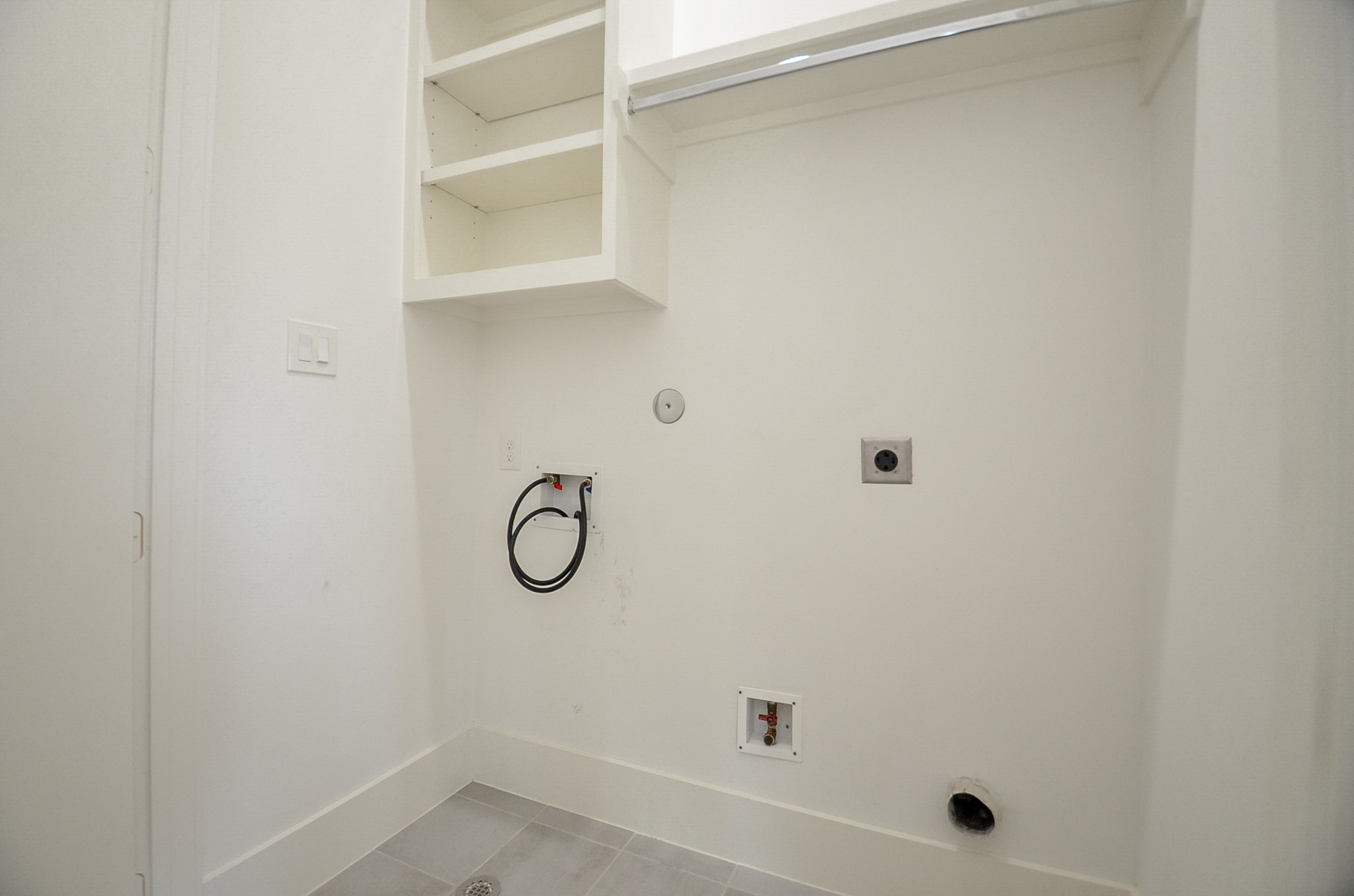 Dedicated upstairs laundry space with built-in shelving and a hanging rod.
