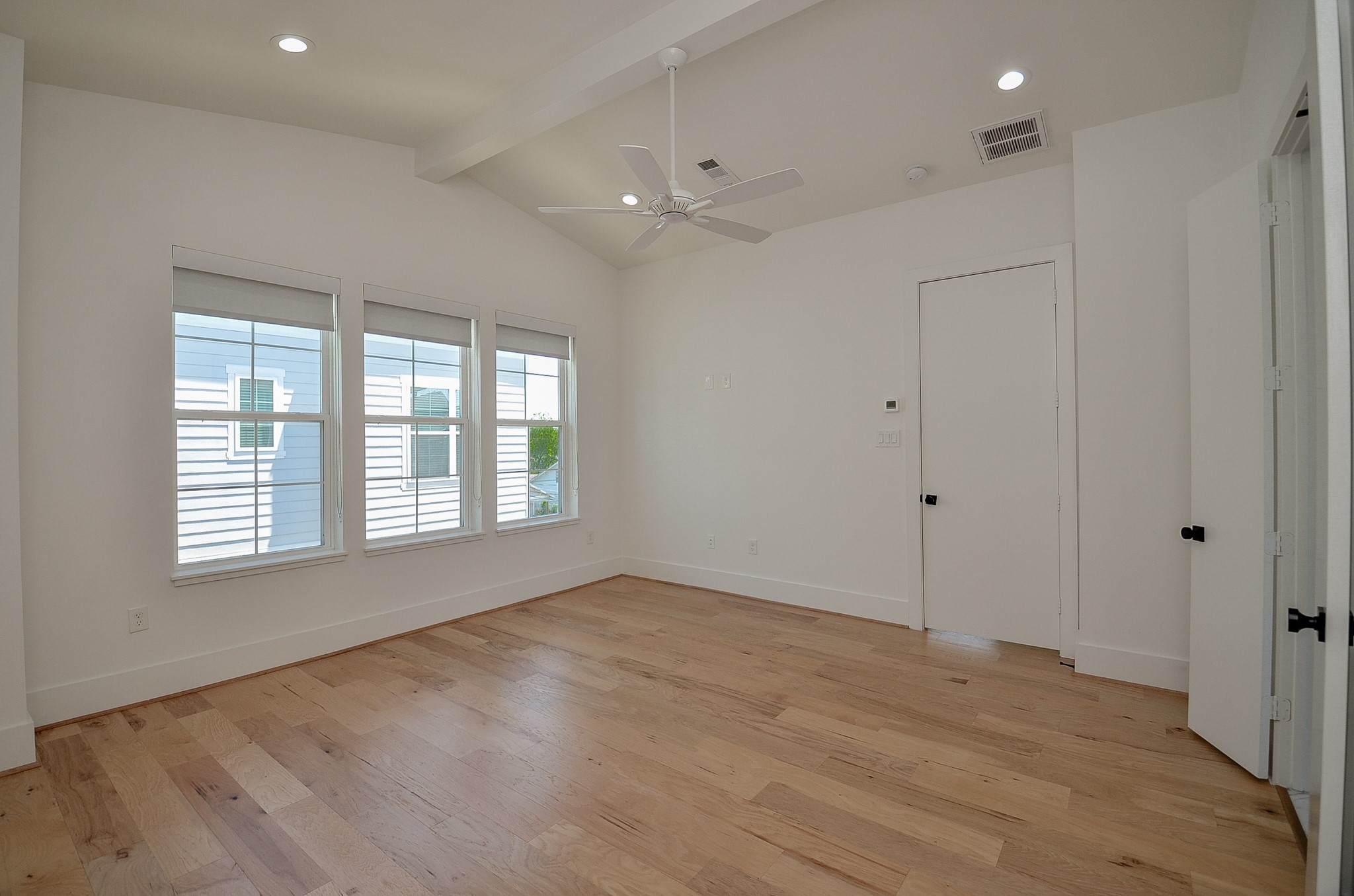 An unfurnished view of the primary bedroom shows its windows, flooring, and available space.