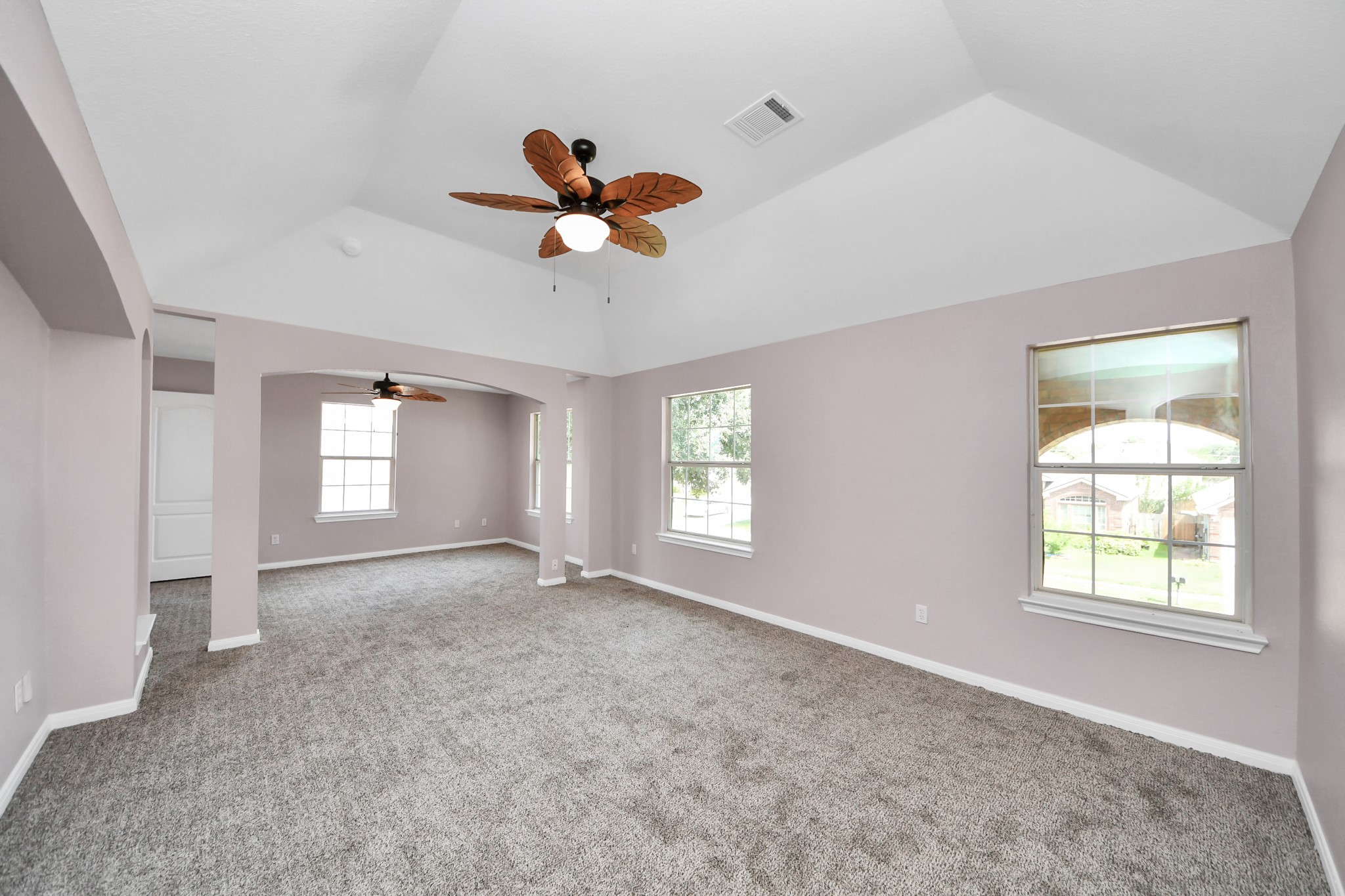 Spacious and airy primary living area featuring vaulted ceilings, elegant archways, and abundant natural light, creating a perfect blend of comfort and style.