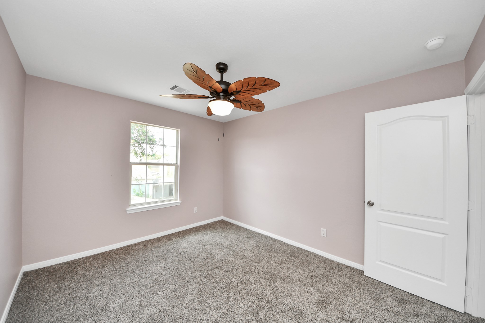Experience comfort and style in this inviting bedroom, featuring plush carpeting, a soothing color palette, and a charming ceiling fan.