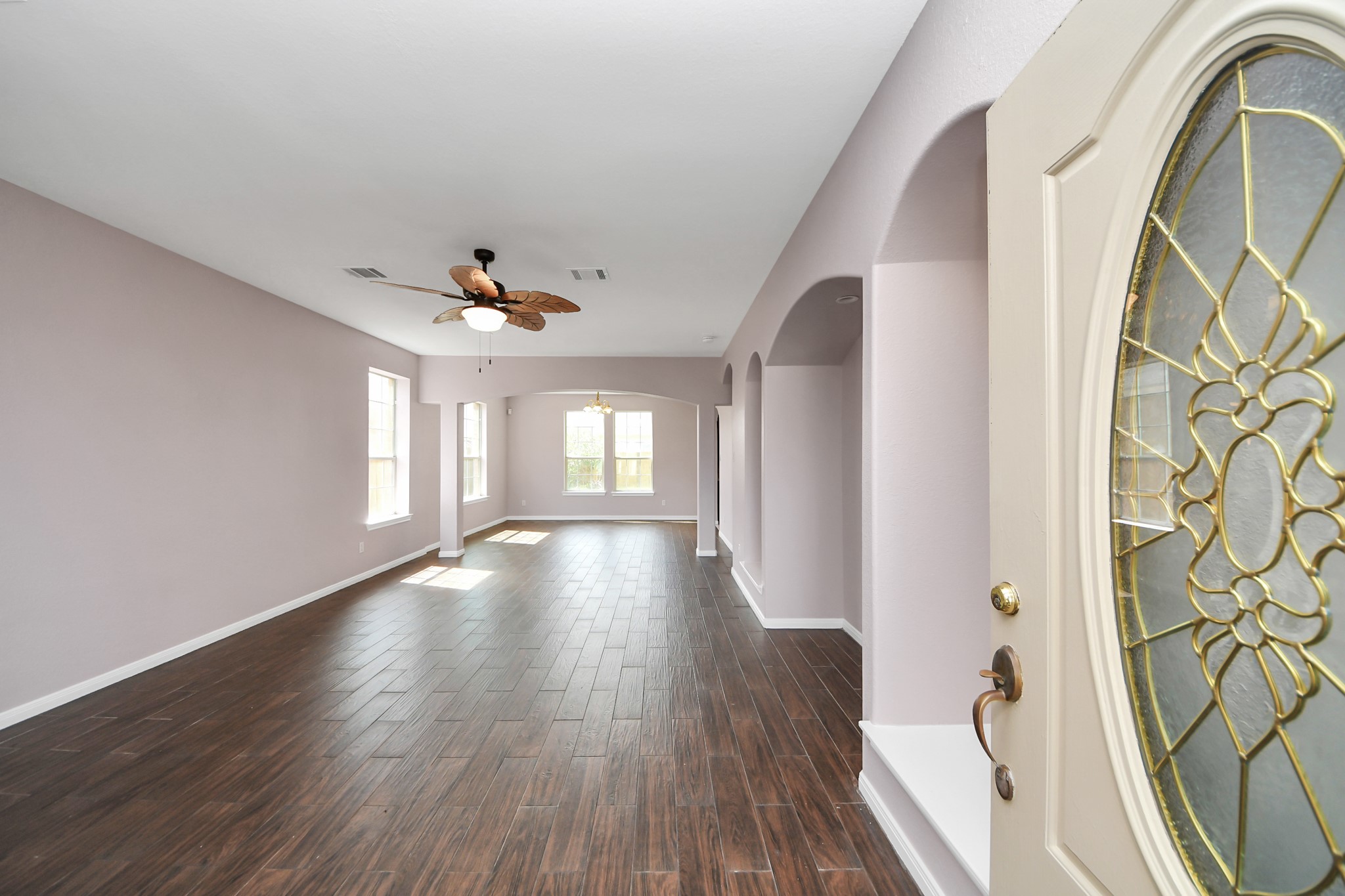 Spacious living area with elegant wood tile flooring, abundant natural light, and a decorative ceiling fan, perfect for modern living. Spacious living area with elegant wood tile flooring, abundant natural light, and a decorative ceiling fan, perfect for modern living.