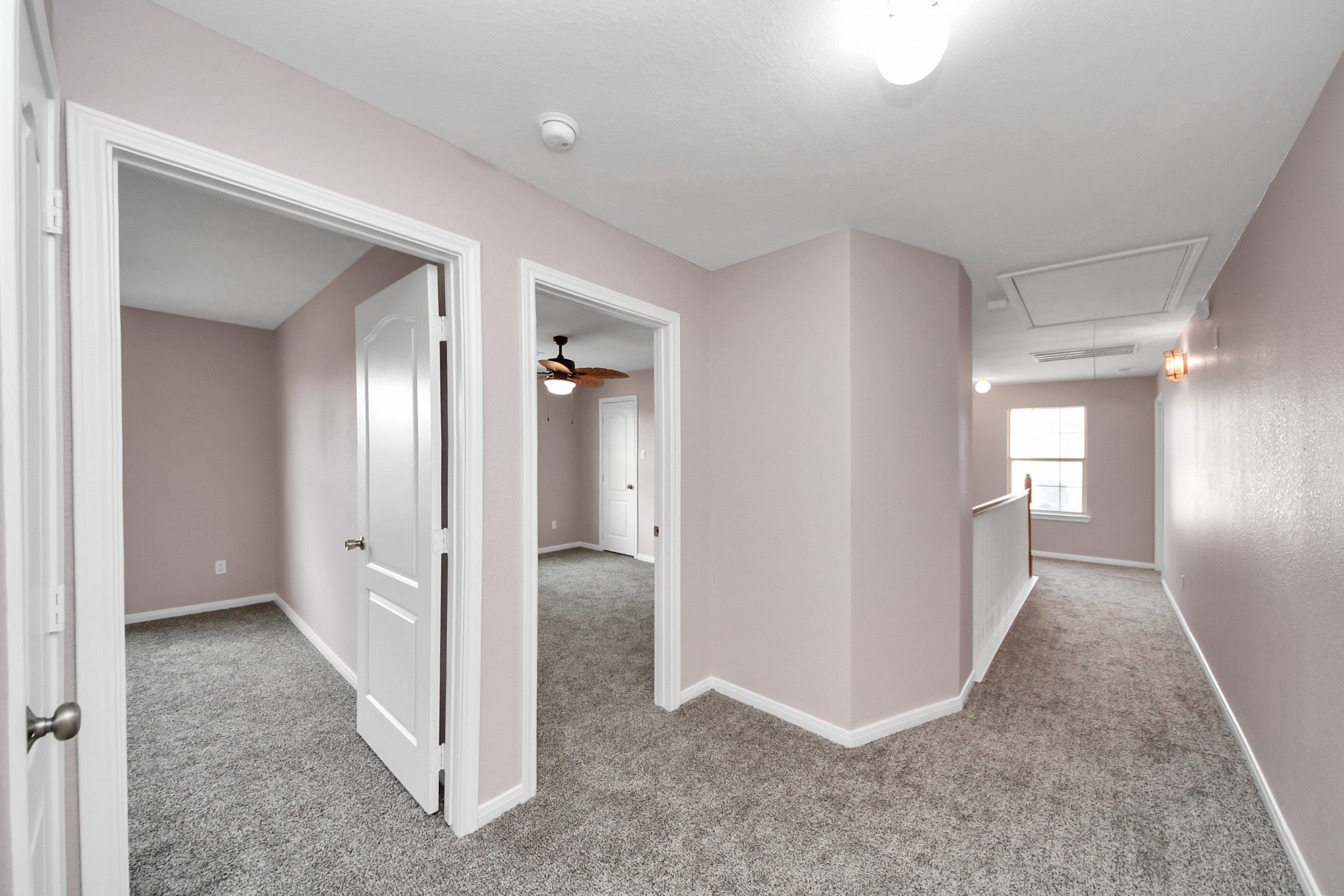 Spacious upper hallway with plush carpeting and access to multiple rooms, featuring a ceiling fan and abundant natural light.