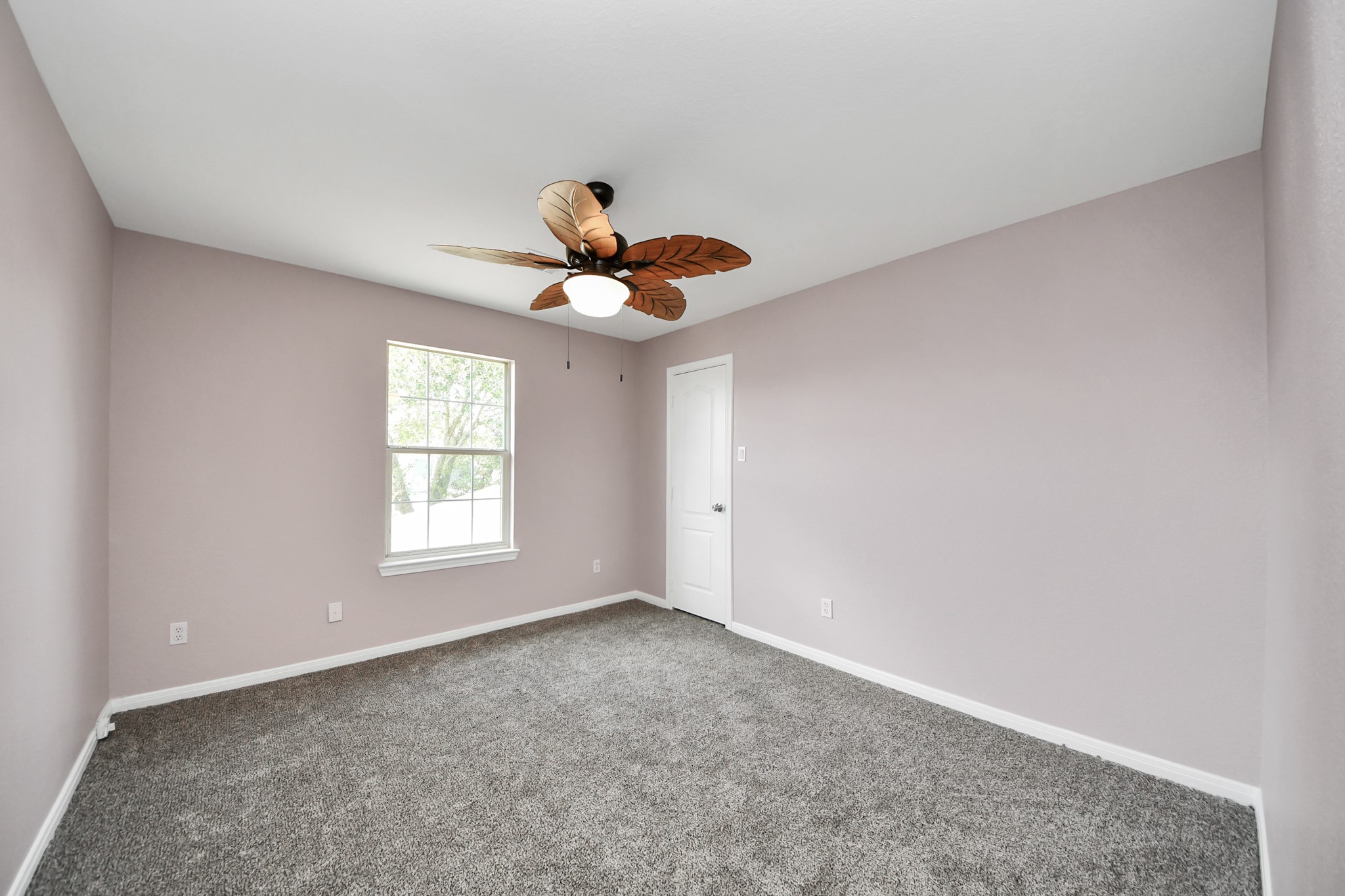 Experience the tranquility of Bed 4, featuring soft lavender walls, plush carpeting, and a charming ceiling fan, perfect for restful nights.
