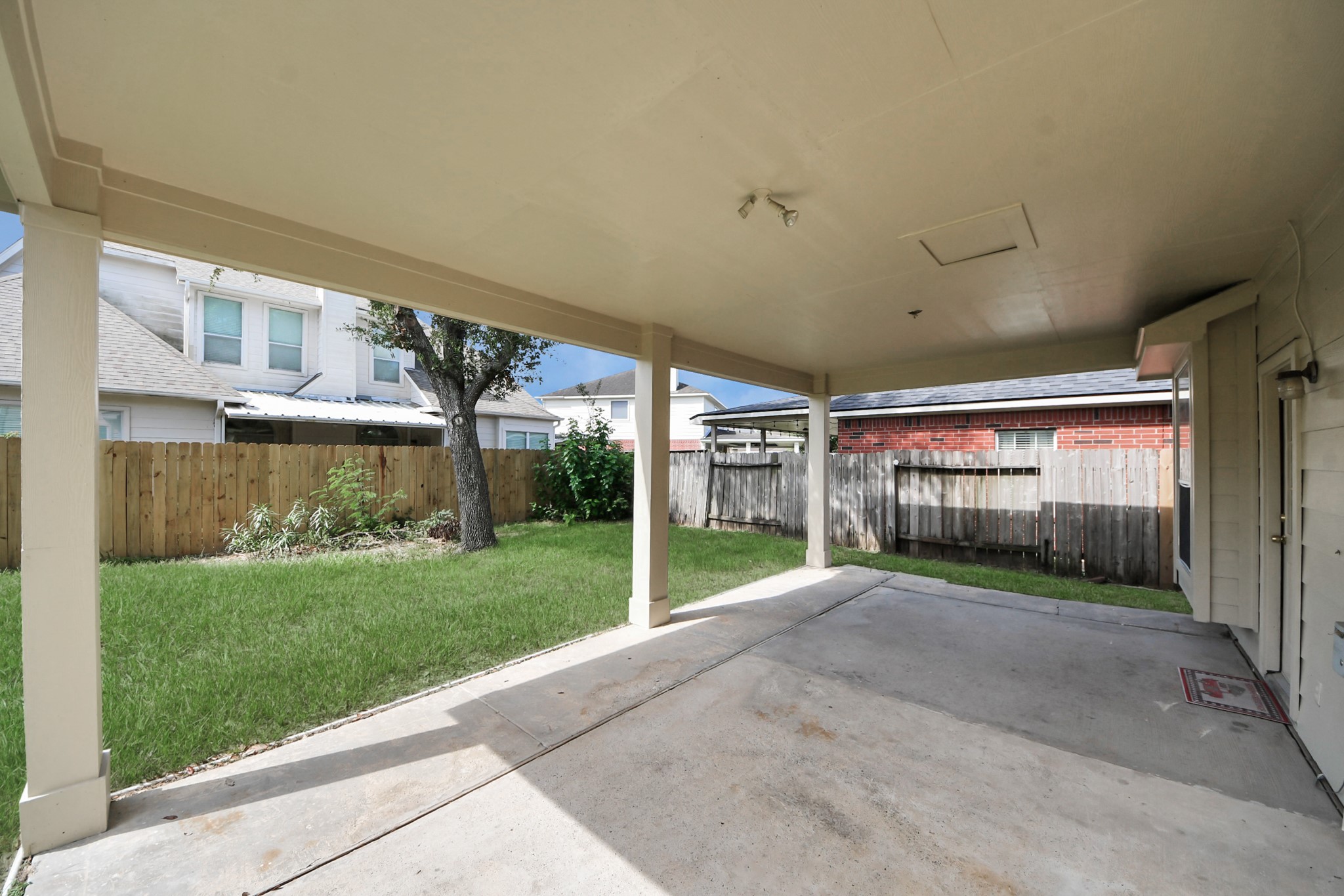 Spacious covered patio overlooking a lush green backyard, perfect for outdoor relaxation and entertainment.