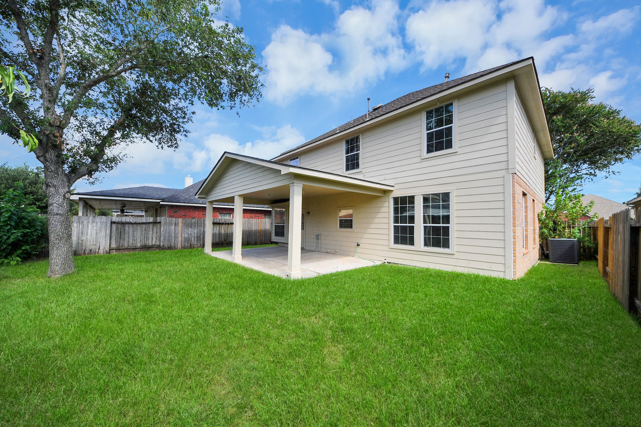 Spacious backyard with a covered patio, perfect for outdoor gatherings, complemented by a well-maintained lawn and privacy fencing.
