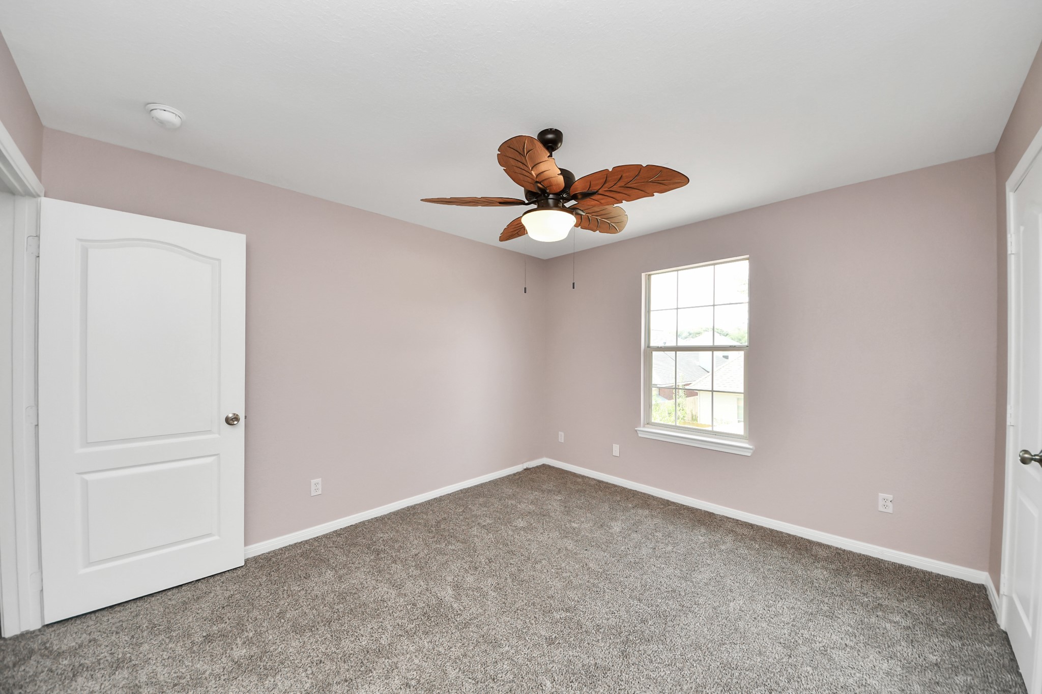 Discover the charm of this cozy bedroom featuring plush carpeting, a tropical ceiling fan, and abundant natural light.