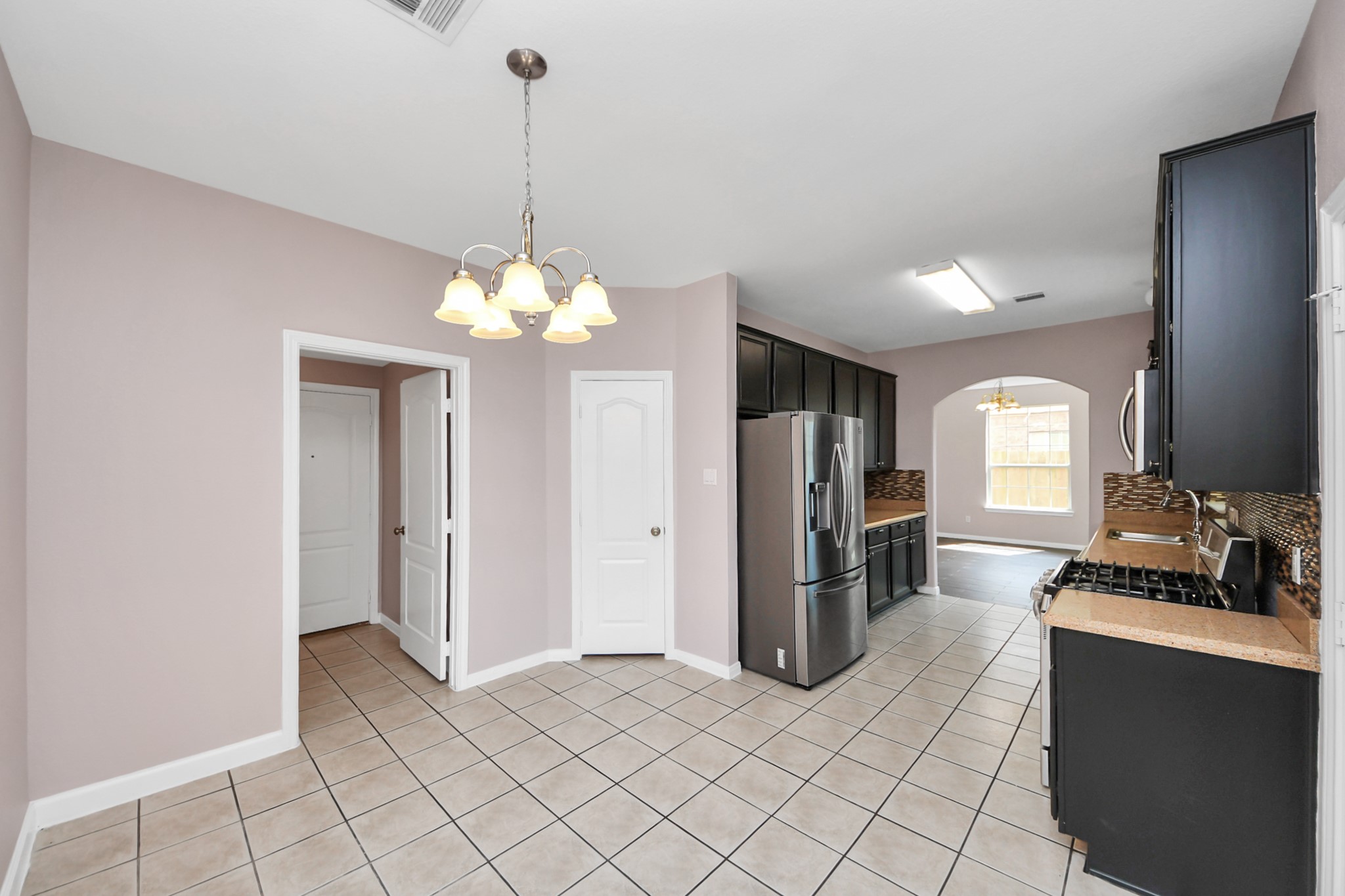 Bright kitchen with modern appliances, sleek dark cabinetry, and a cozy dining area under a stylish light fixture.