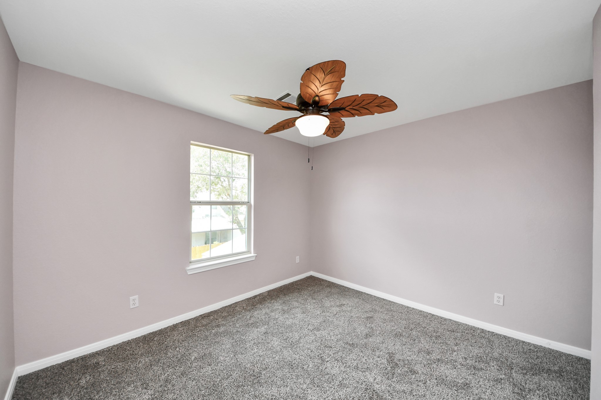 Discover the charm of Bedroom 4, featuring soft pastel walls and plush carpeting, illuminated by natural light from a large window and a stylish ceiling fan.