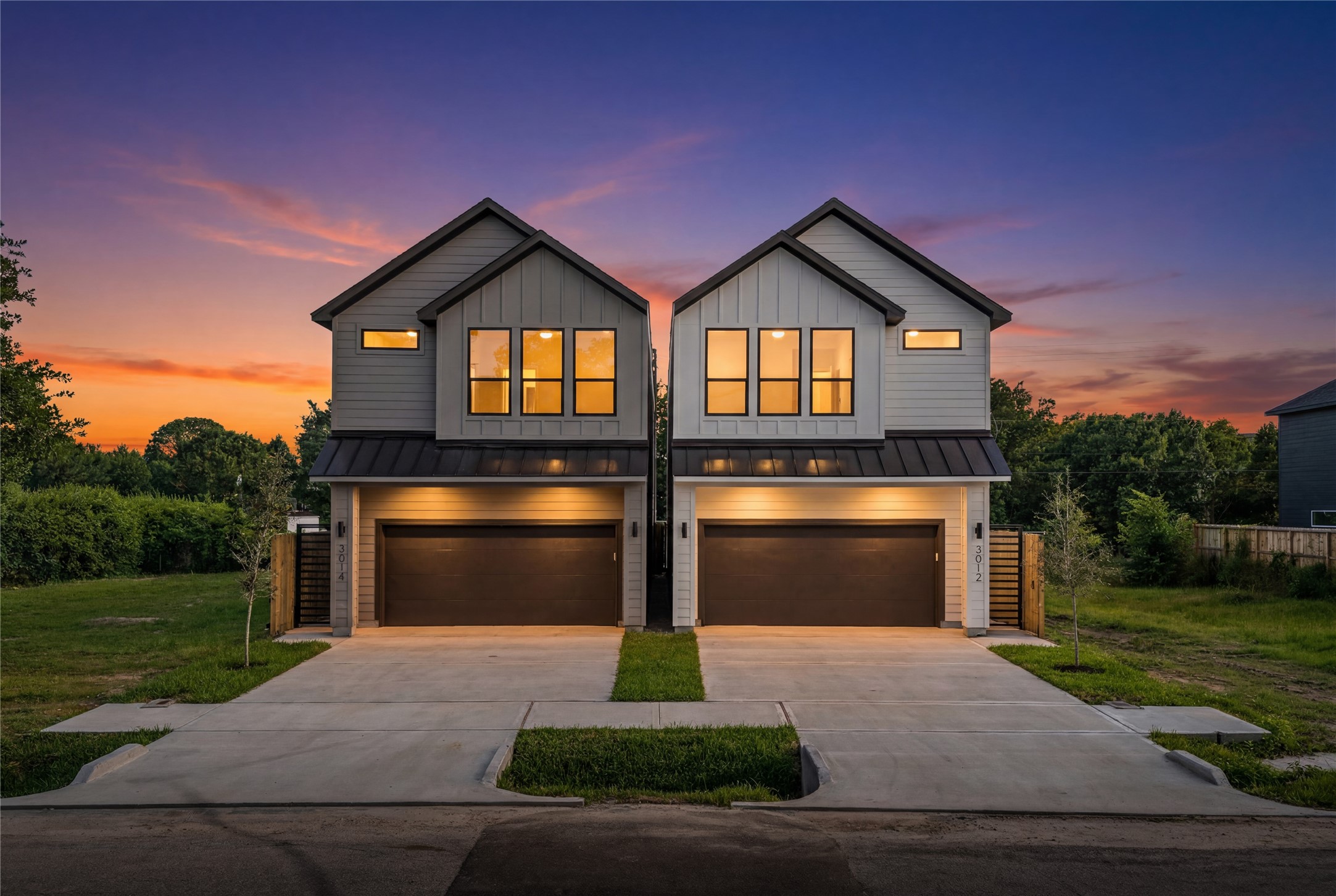 This modern home offers great curb appeal, featuring a clean white and grey exterior and two wide concrete driveways. Warm interior lighting makes the space feel instantly inviting from the street. Its a sharp, balanced, and well-designed property that is completely move-in ready.