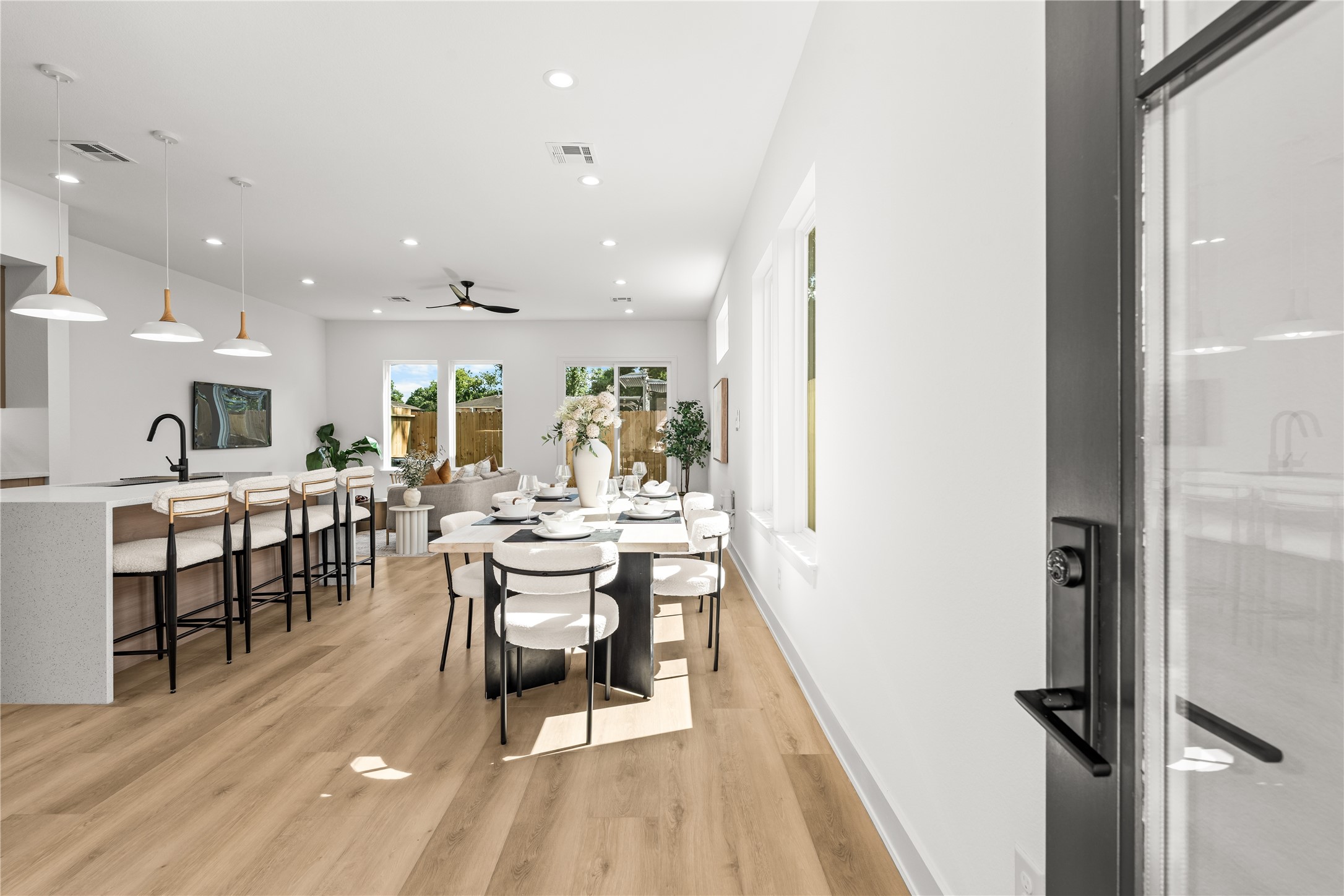 Inside, the open layout immediately feels spacious and bright, with light flooring connecting the living and dining areas. The kitchen features a large island with a white quartz waterfall countertop, making it a natural setup for quick meals or casual hanging out.
