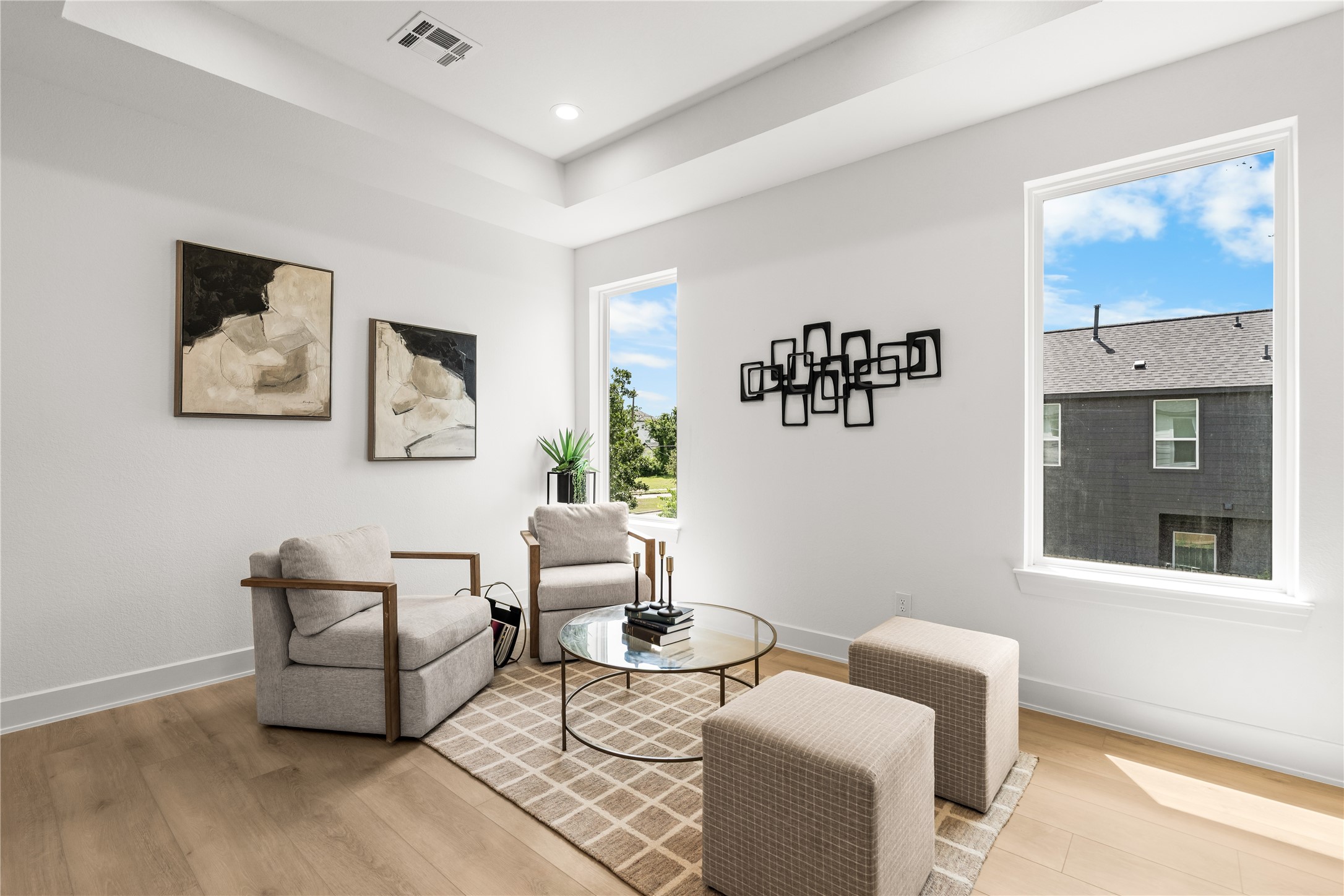 This view shows the size and natural light of the upper lounge. Large windows look out over the neighborhood and keep the room bright, while the open layout easily fits multiple chairs, accent cubes, and a coffee table.