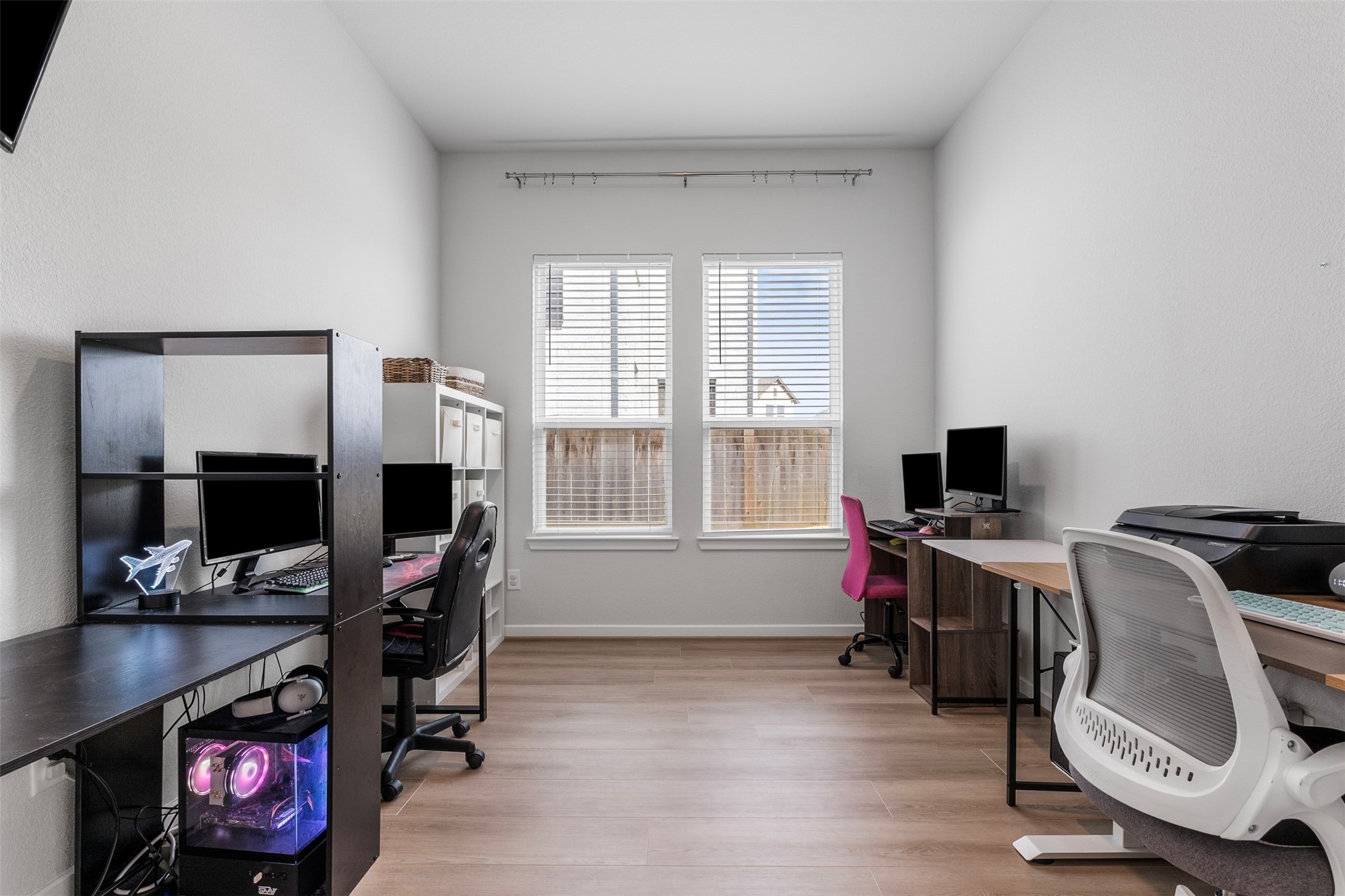 A large office with luxury vinyl flooring and natural light, roomy enough for several workstations, also has French doors.
