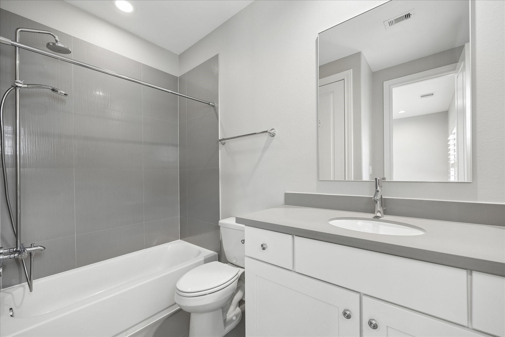En-suite bath for 3rd floor bedroom. Modern bathroom featuring sleek gray tile, a spacious bathtub with an overhead shower, and a stylish vanity with ample storage.