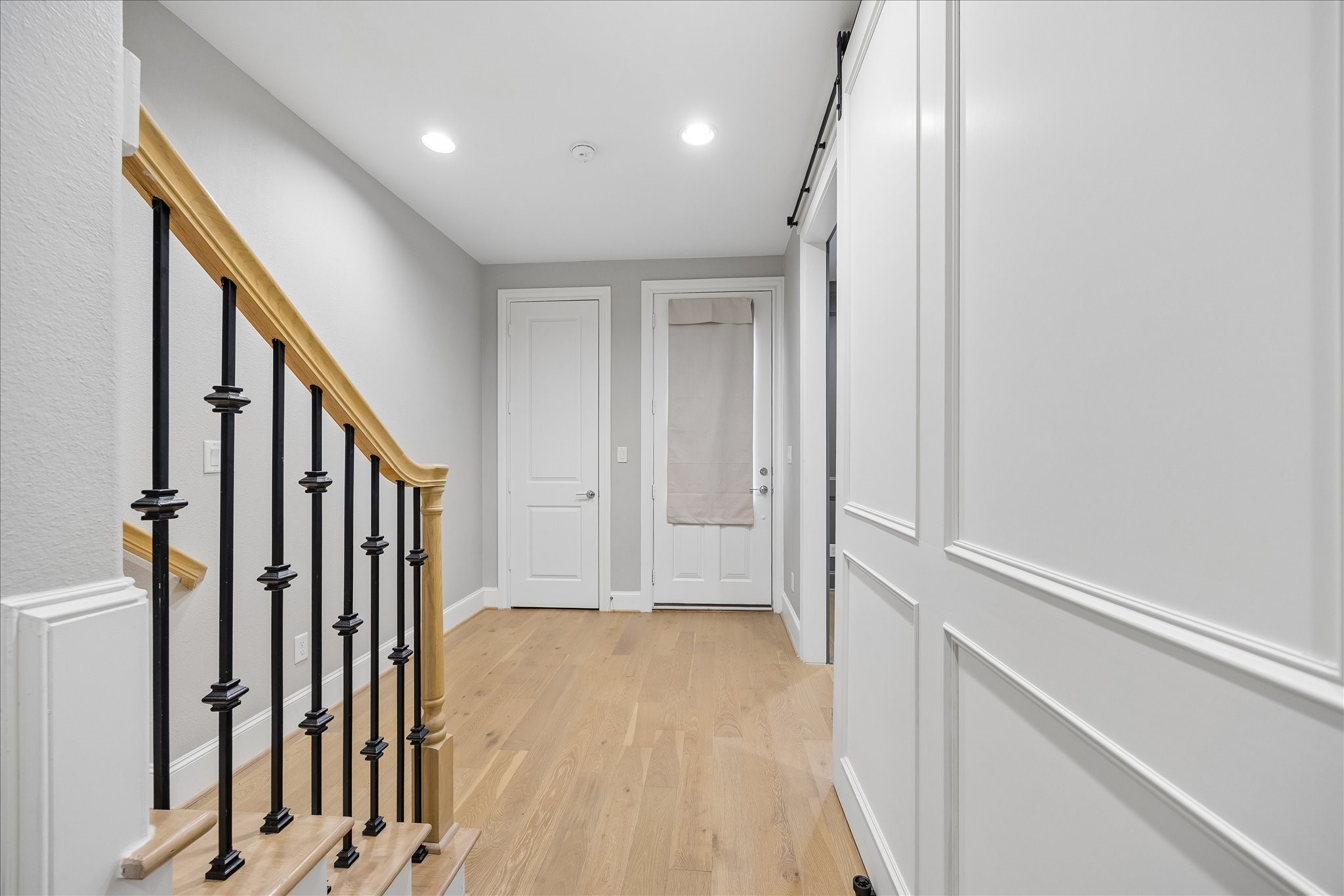 Bright and inviting entryway featuring elegant wood flooring, stylish railing, and modern finishes with large coat closet.