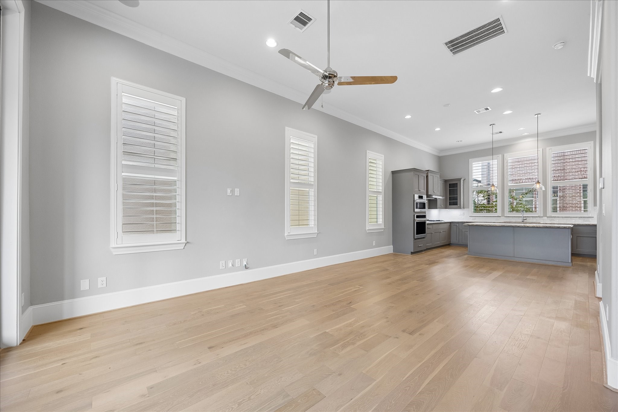 Spacious open-concept living area with beautiful hardwood floors, modern kitchen featuring granite countertops, and abundant natural light from large windows.