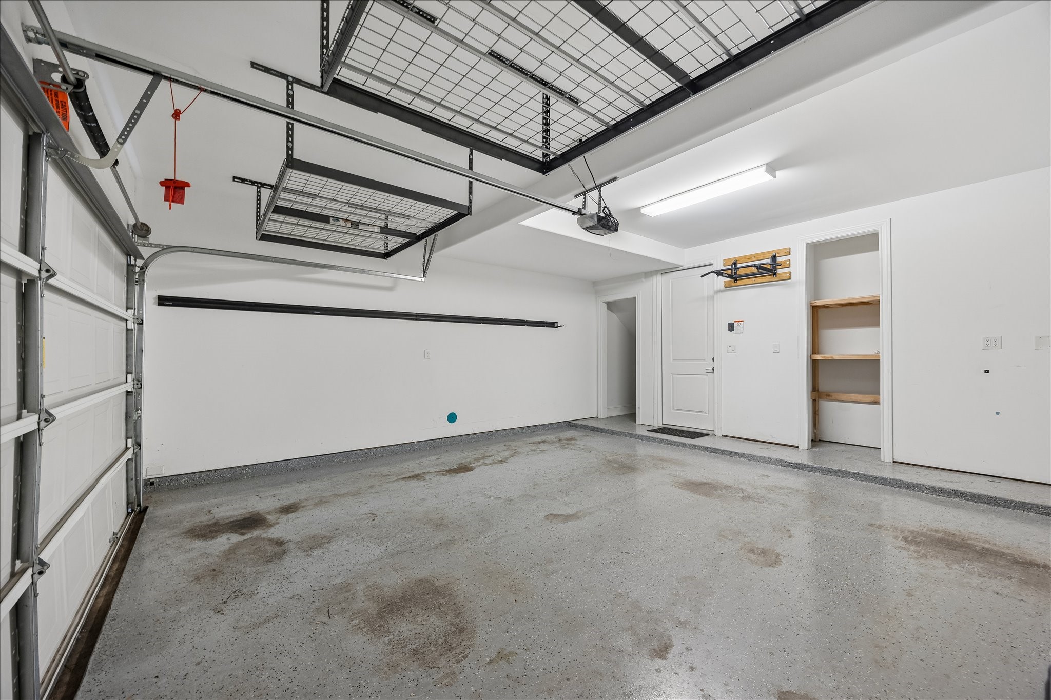 Spacious and clean garage featuring ample storage shelves, overhead racks, and convenient interior access.