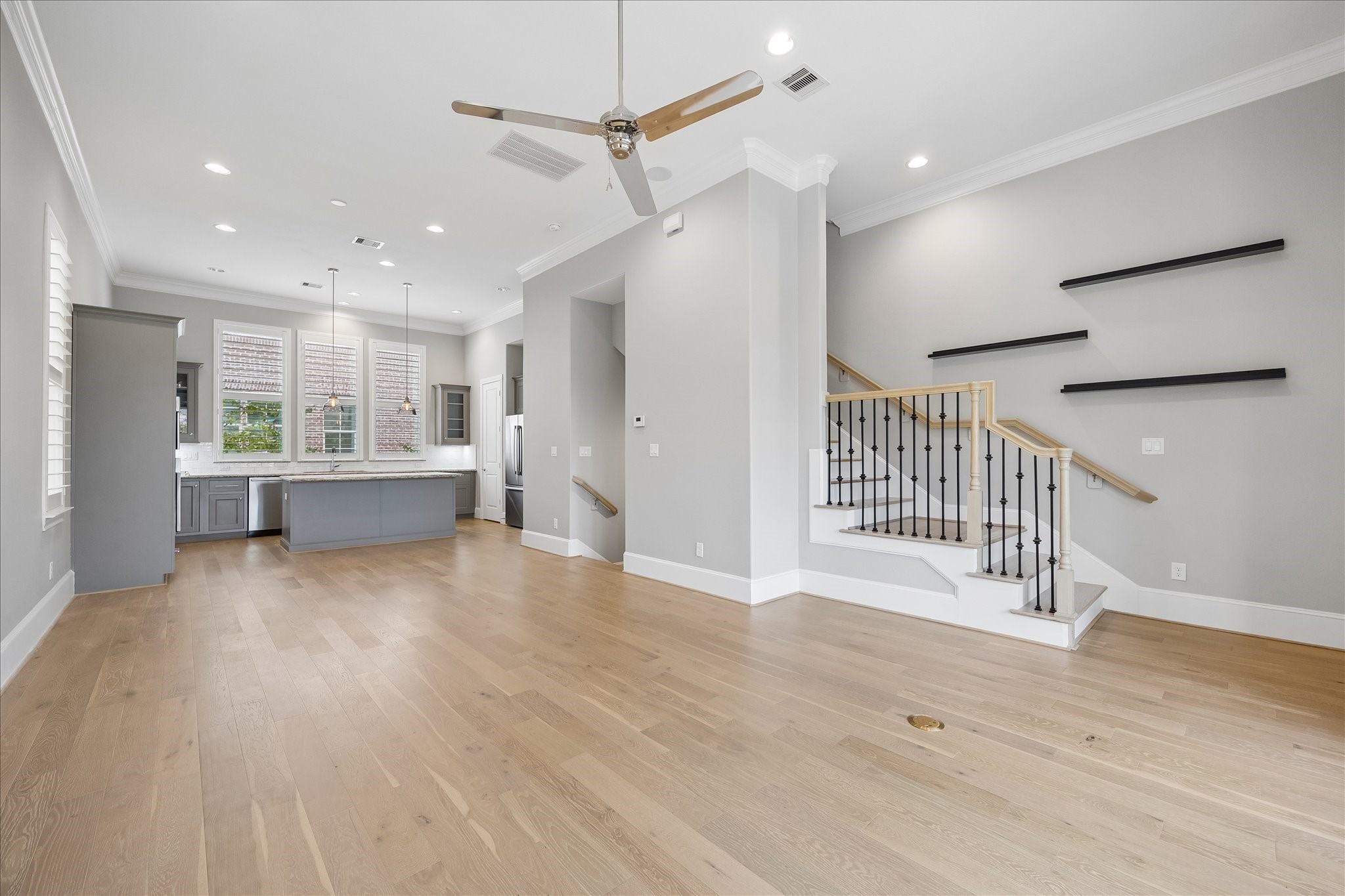 Spacious open-concept living area with elegant hardwood floors, modern kitchen with sleek cabinetry and large island, and a stylish staircase with contemporary railing design.