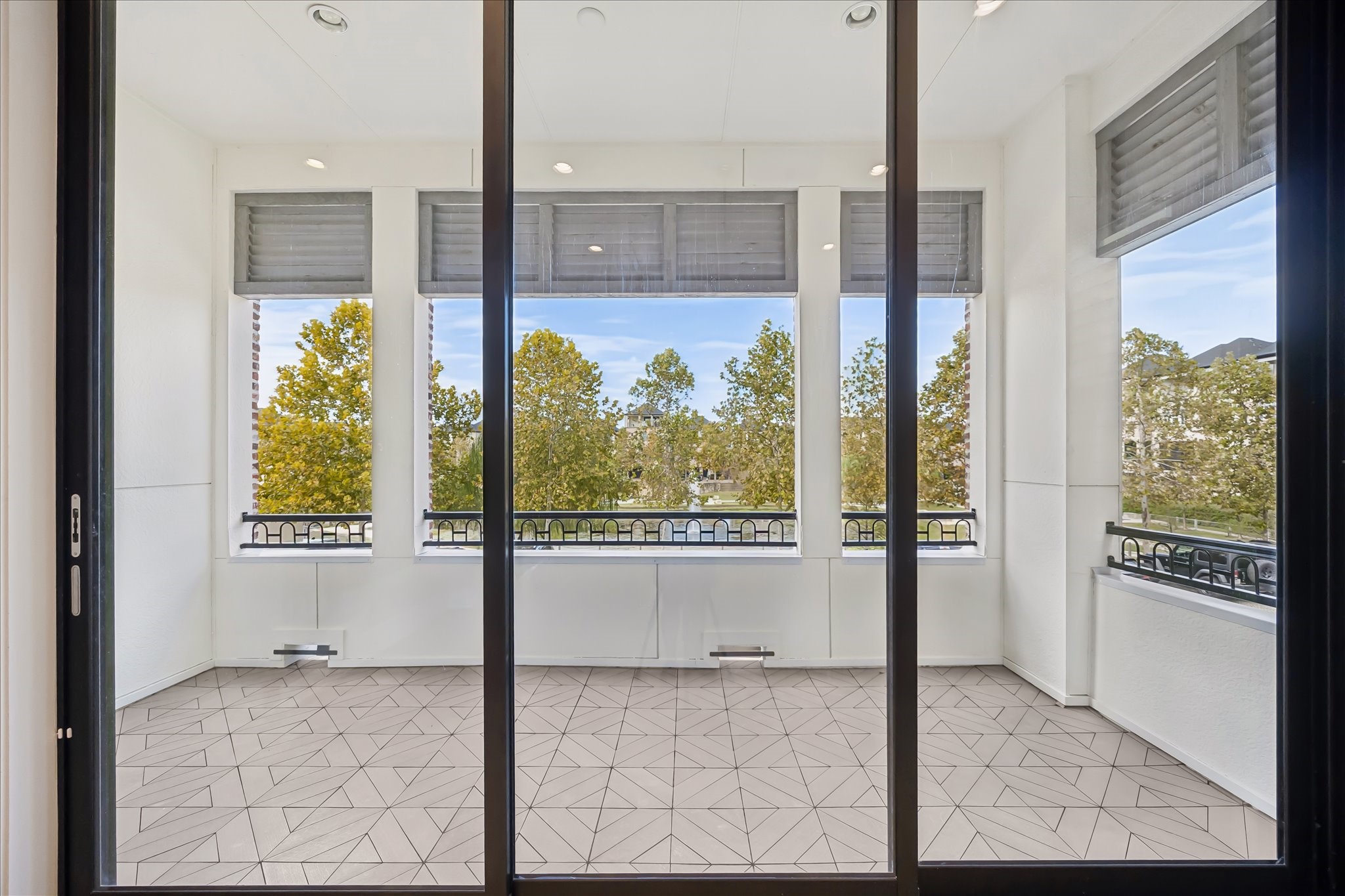 Spacious balcony with large windows offering serene views of lush trees, Lake, and fountain with stylish tiled floor, perfect for relaxation or entertaining.  The 3 panel windows/sliding glass doors open.  See previous pictures.