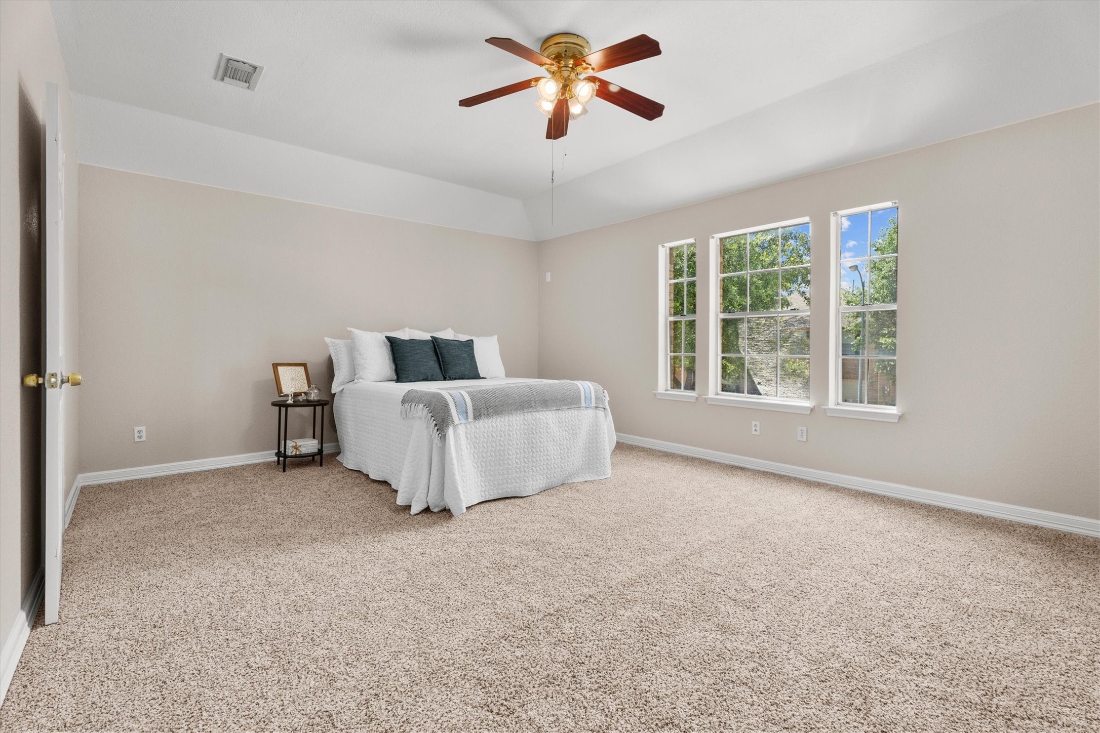 Spacious primary bedroom featuring vaulted ceilings and plush carpeting.
