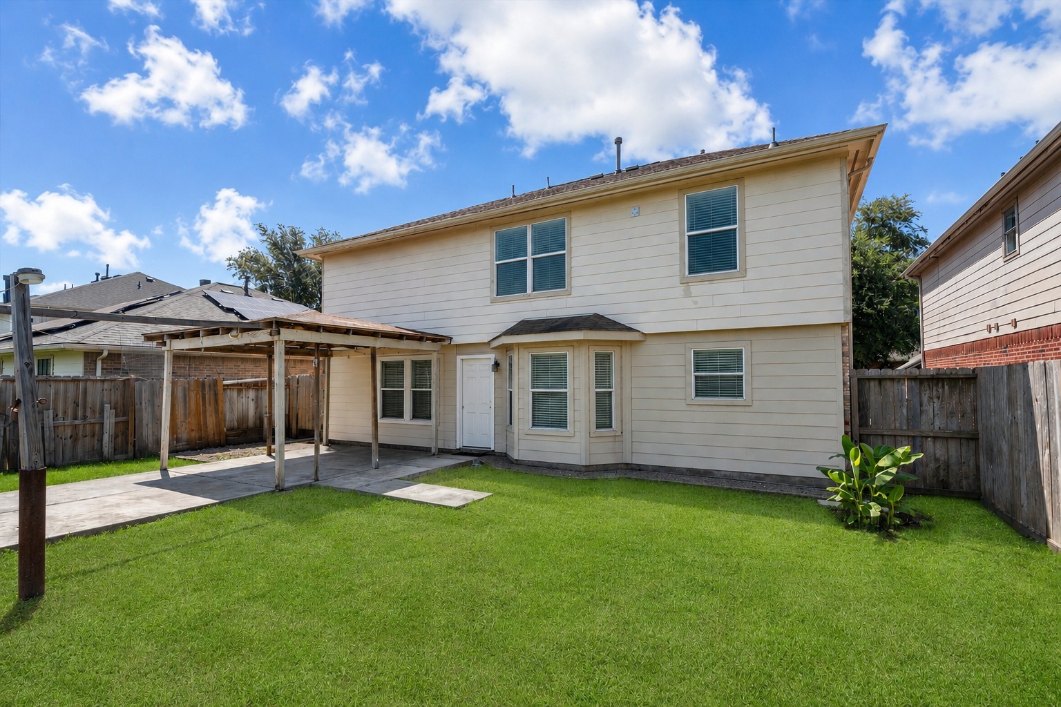 Spacious backyard featuring a covered patio, open green space, and room for outdoor entertaining, play, gardening, or pets.