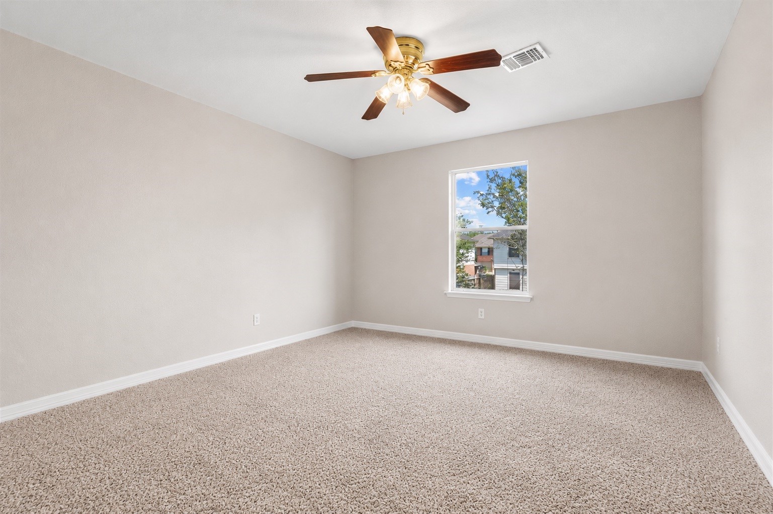 Spacious secondary bedroom with plush carpeting, ceiling fan, and plenty of room for a full bedroom setup.
