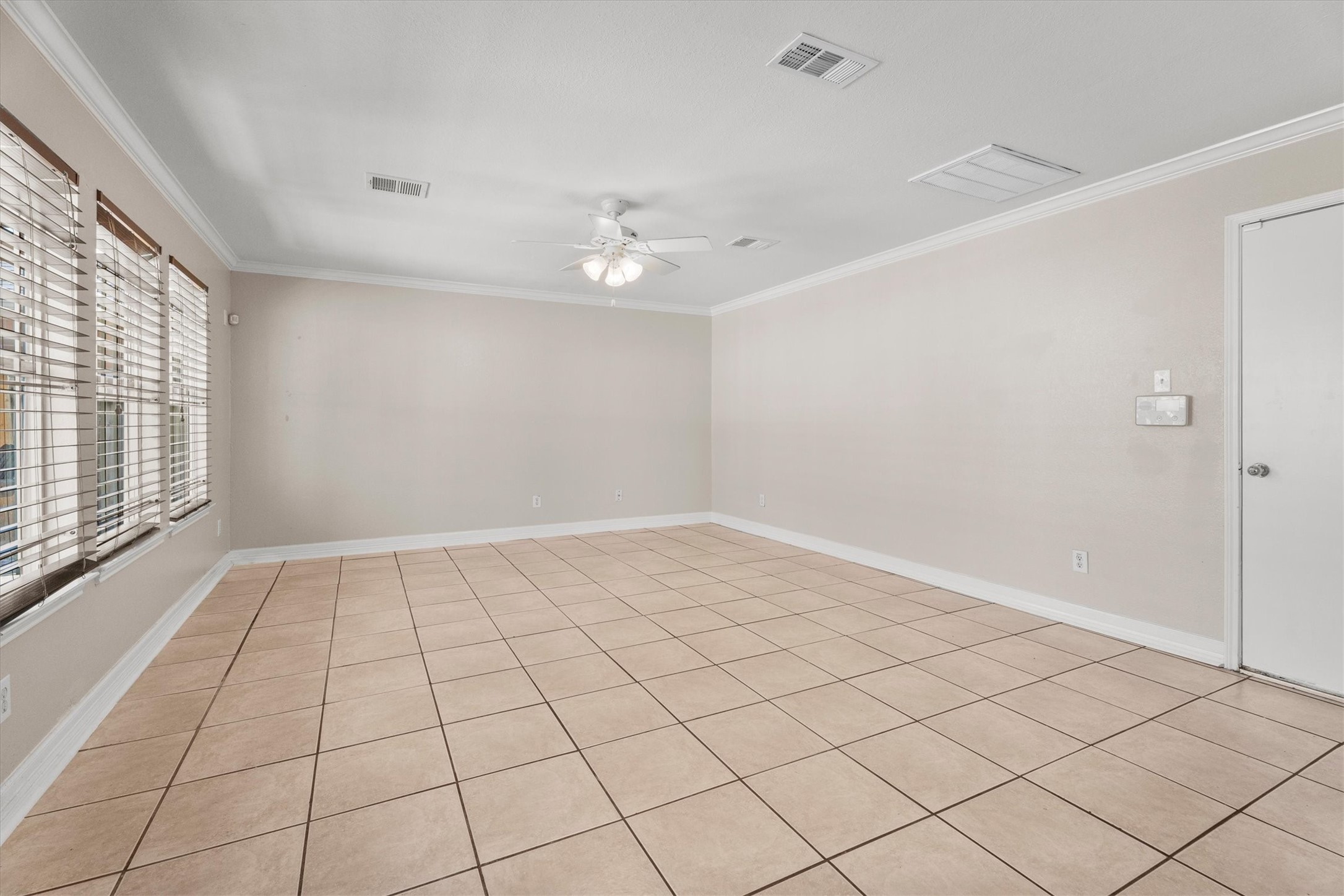 Large family room with tile flooring, abundant wall space for furniture placement, and multiple windows overlooking the backyard.