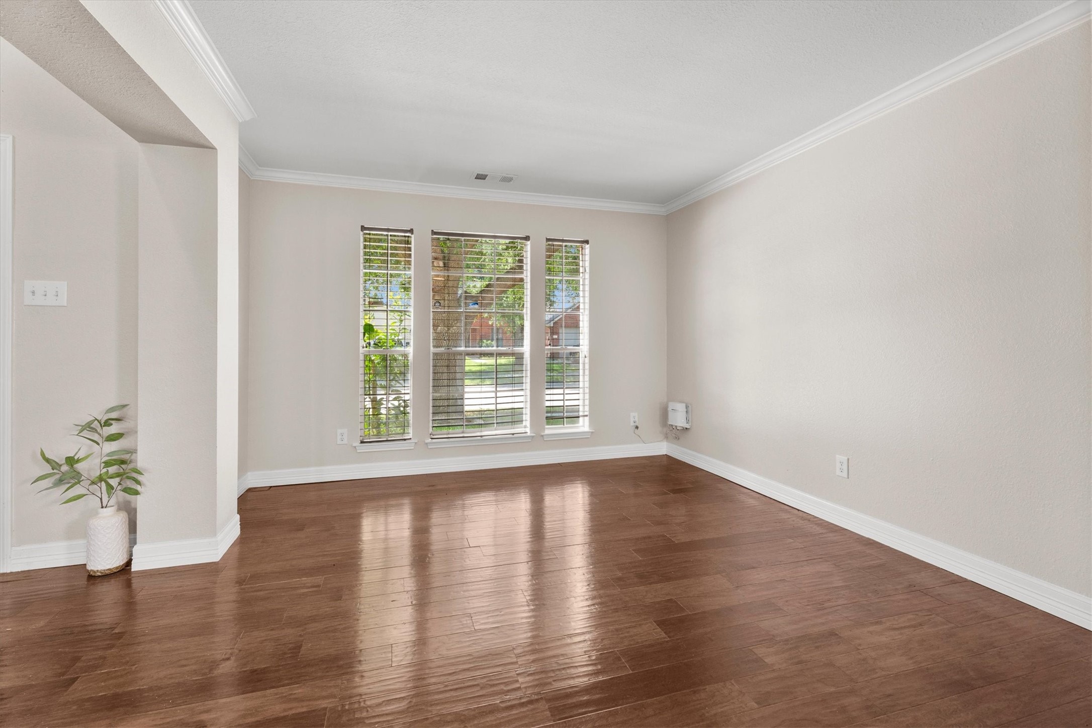 Spacious formal living room with large windows, wood flooring, and flexible space for entertaining or a home office.