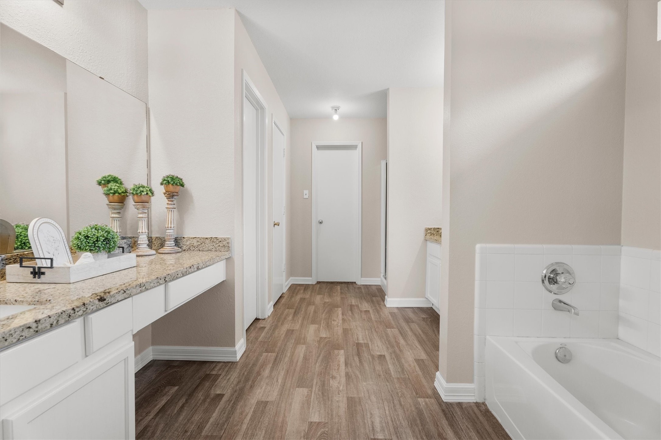 Spacious primary bath featuring dual vanities, a soaking tub, separate shower, and generous storage.