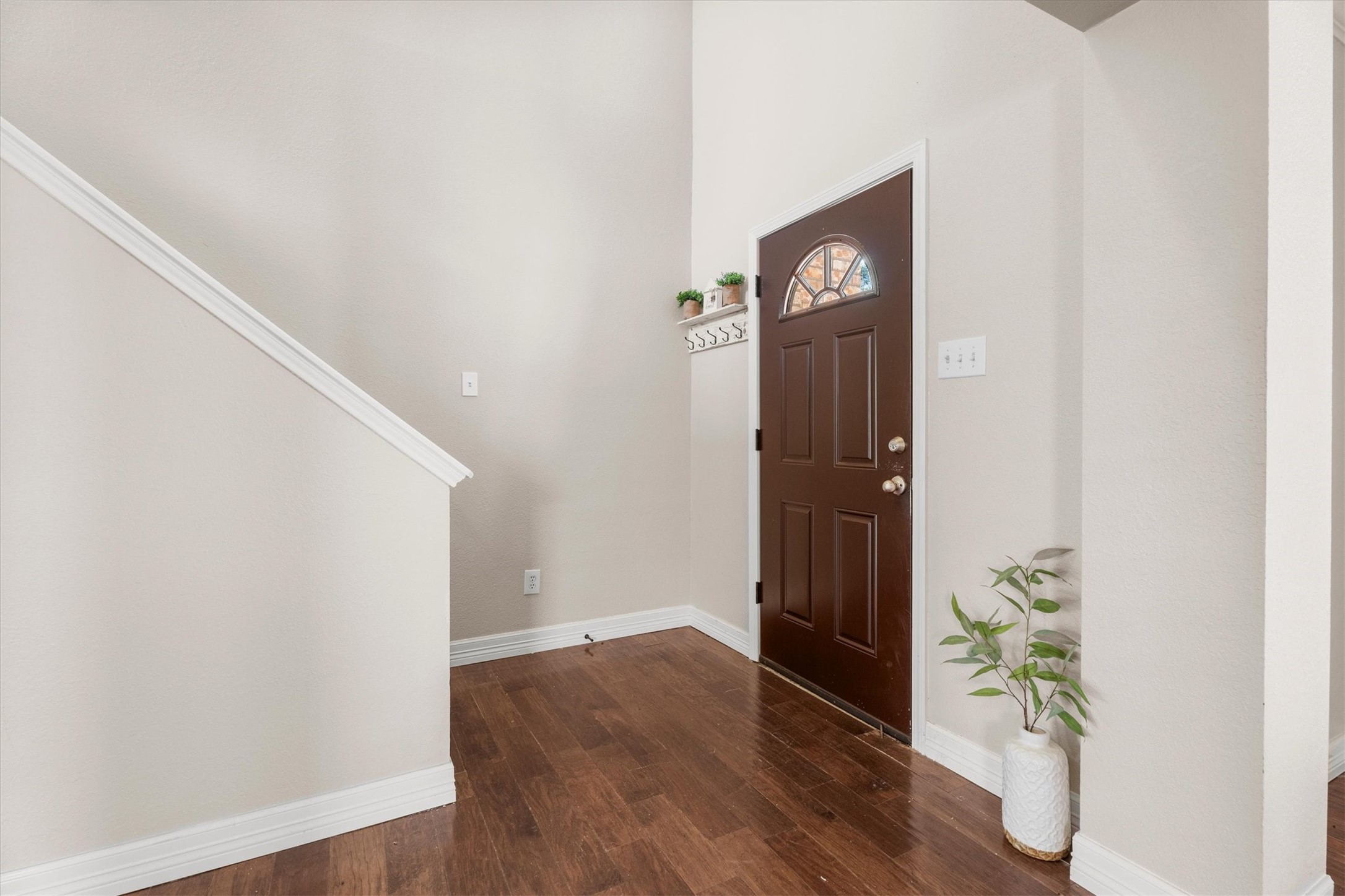 Step inside to a bright foyer featuring soaring ceilings, rich wood flooring, and an open, airy feel.