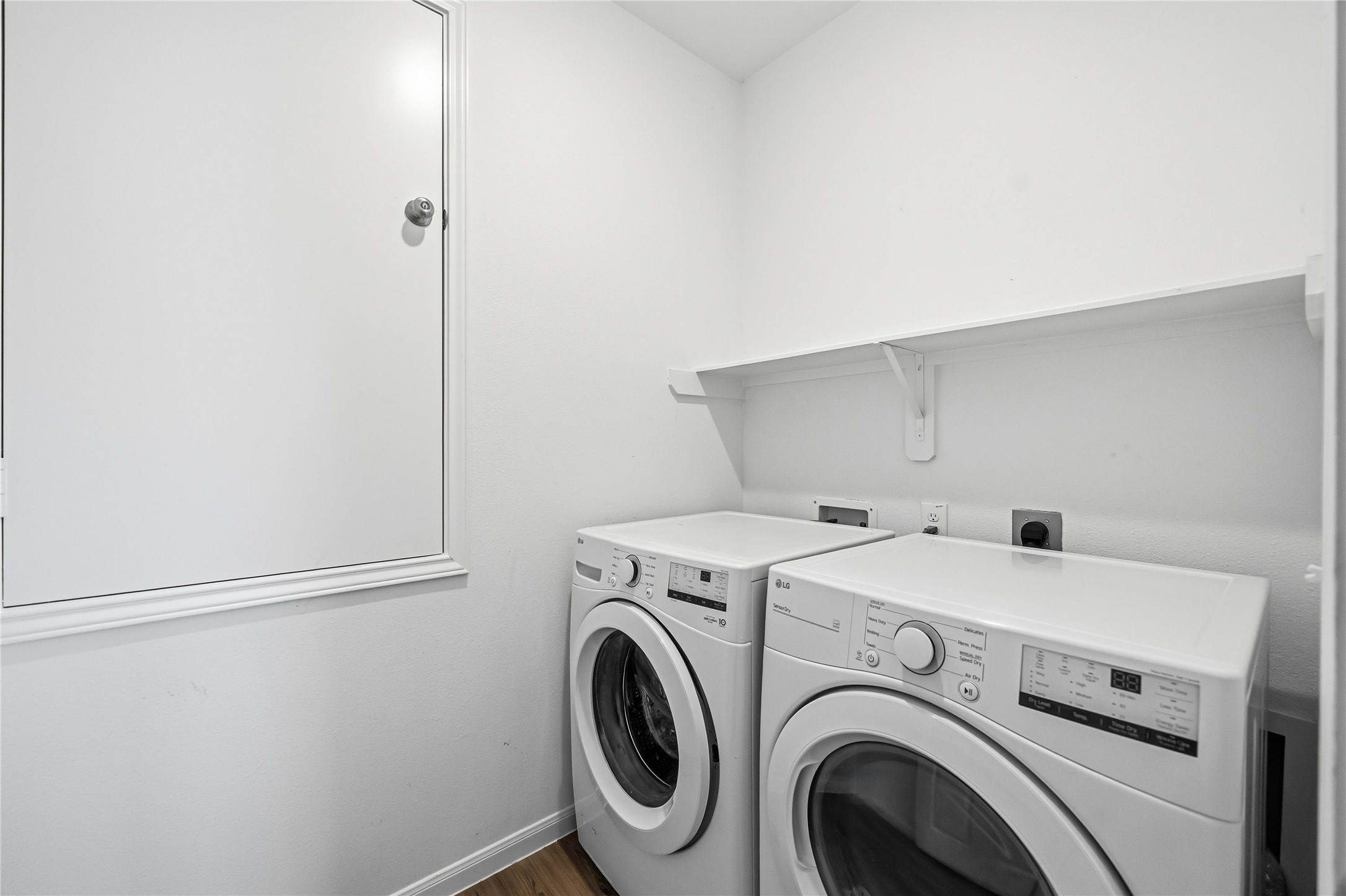 Laundry room with overhead shelving and space for side-by-side appliances.
