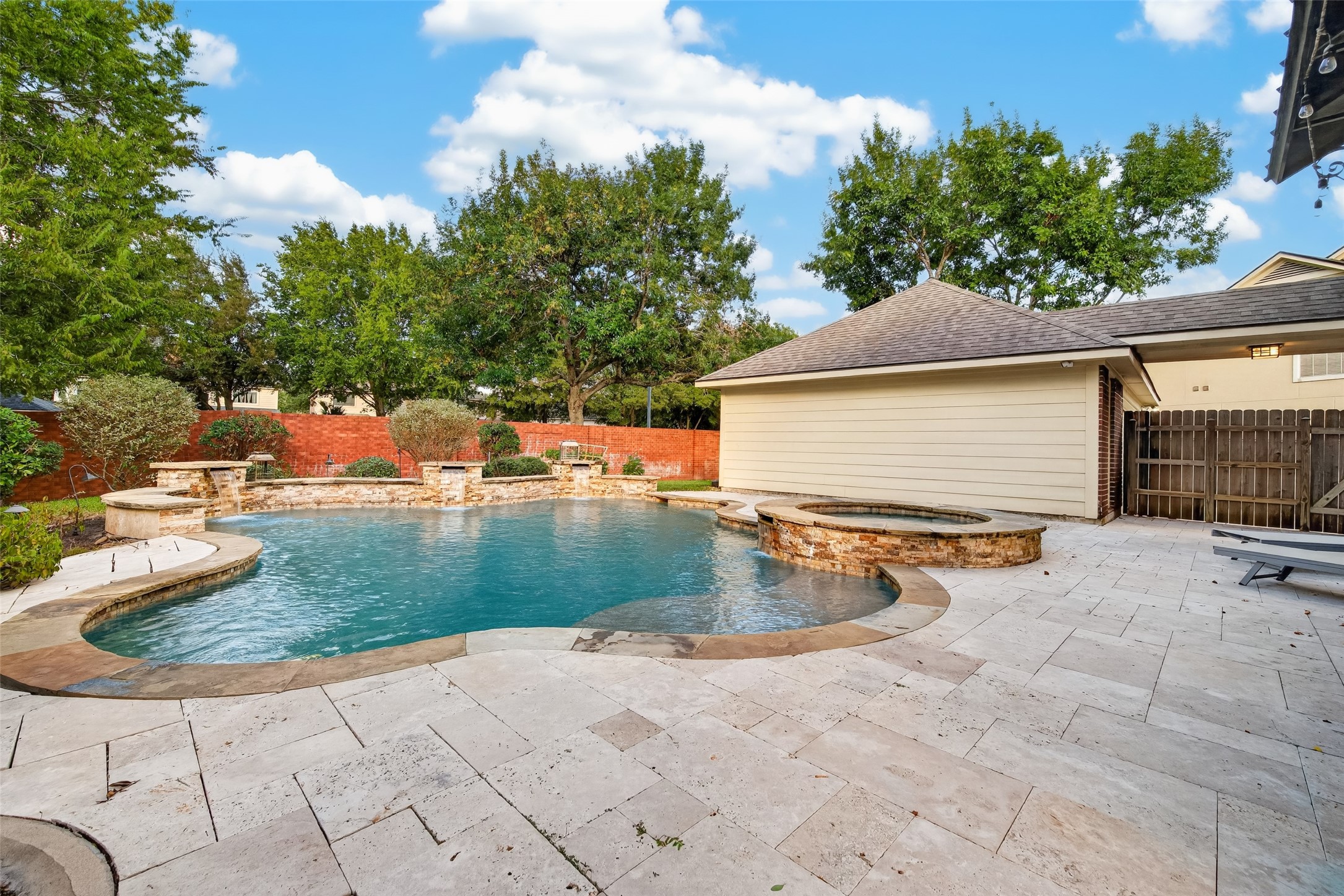 YOUR OWN BACKYARD PARADISE! This gorgeous freeform pool features a PebbleTec finish, natural stone accents, cascading waterfalls & an elevated spa. Surrounded by expansive Travertine decking and mature landscaping, it's a wonderful setting for cooling off on a warm Texas afternoon or simply relaxing beside the water.