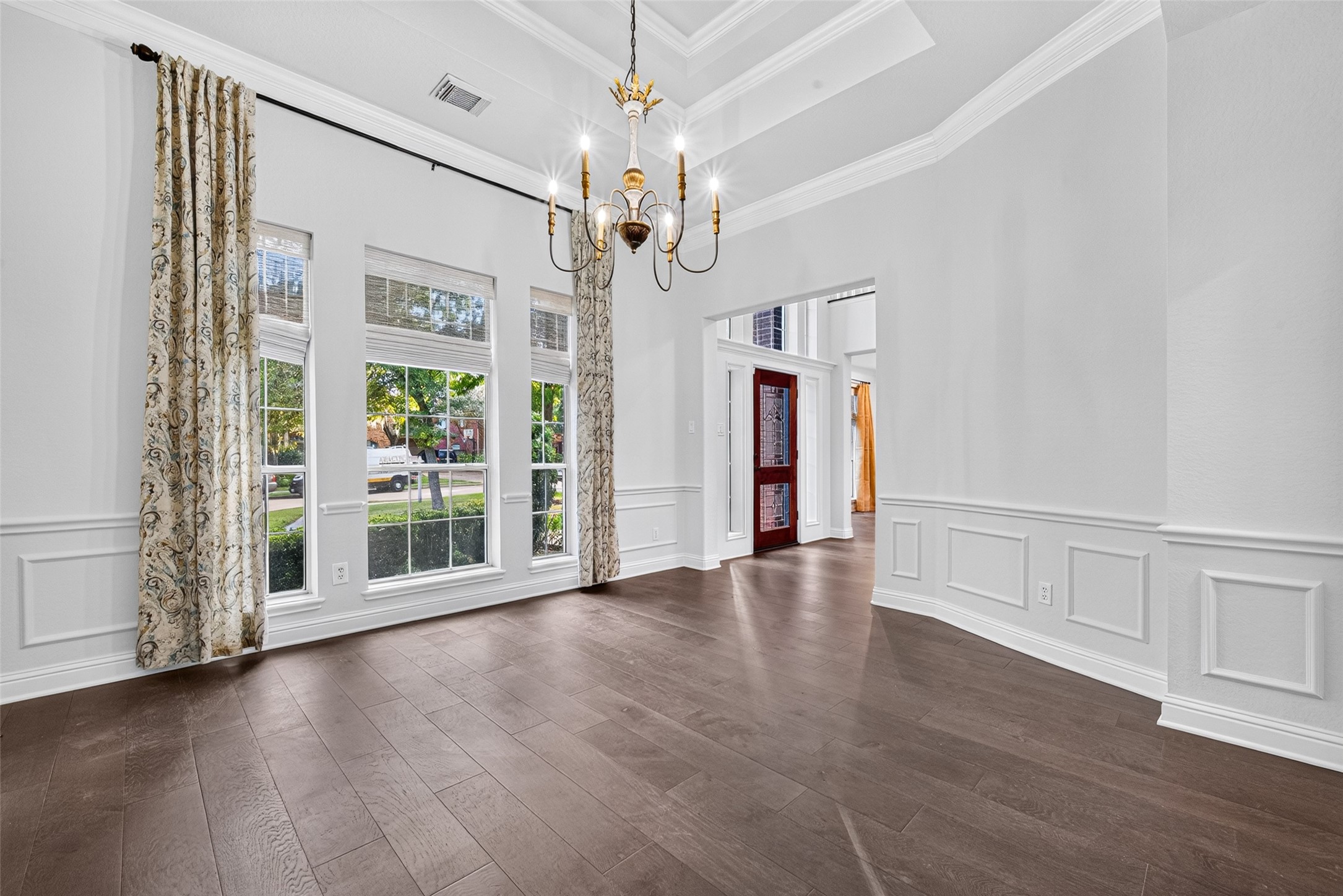 A BEAUTIFUL SETTING FOR MEMORABLE GATHERINGS! The Formal Dining Room welcomes you with a lovely tray ceiling, crown and chair-rail molding, and an elegant chandelier. Three tall windows with woven blinds & decorative draperies bring natural light into the room, while beautiful wood flooring adds warmth. Imagine holiday dinners, special celebrations or simply gathering around the table to share a wonderful meal.
